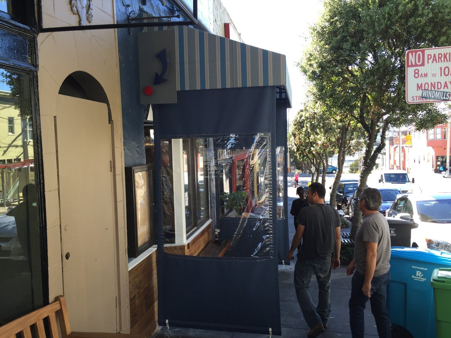 A group of people are walking down a sidewalk in front of a building.