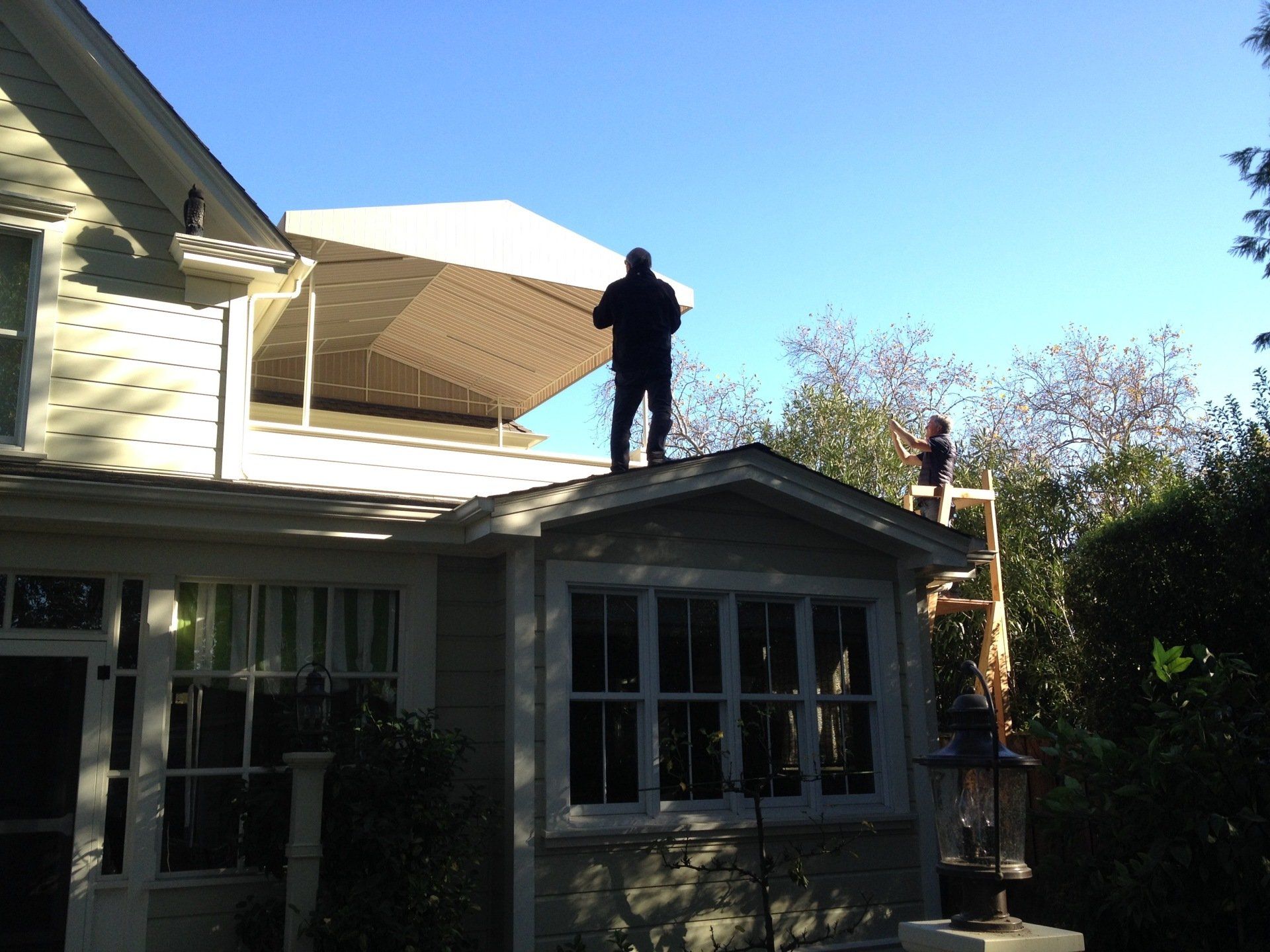 Two men are working on the roof of a house