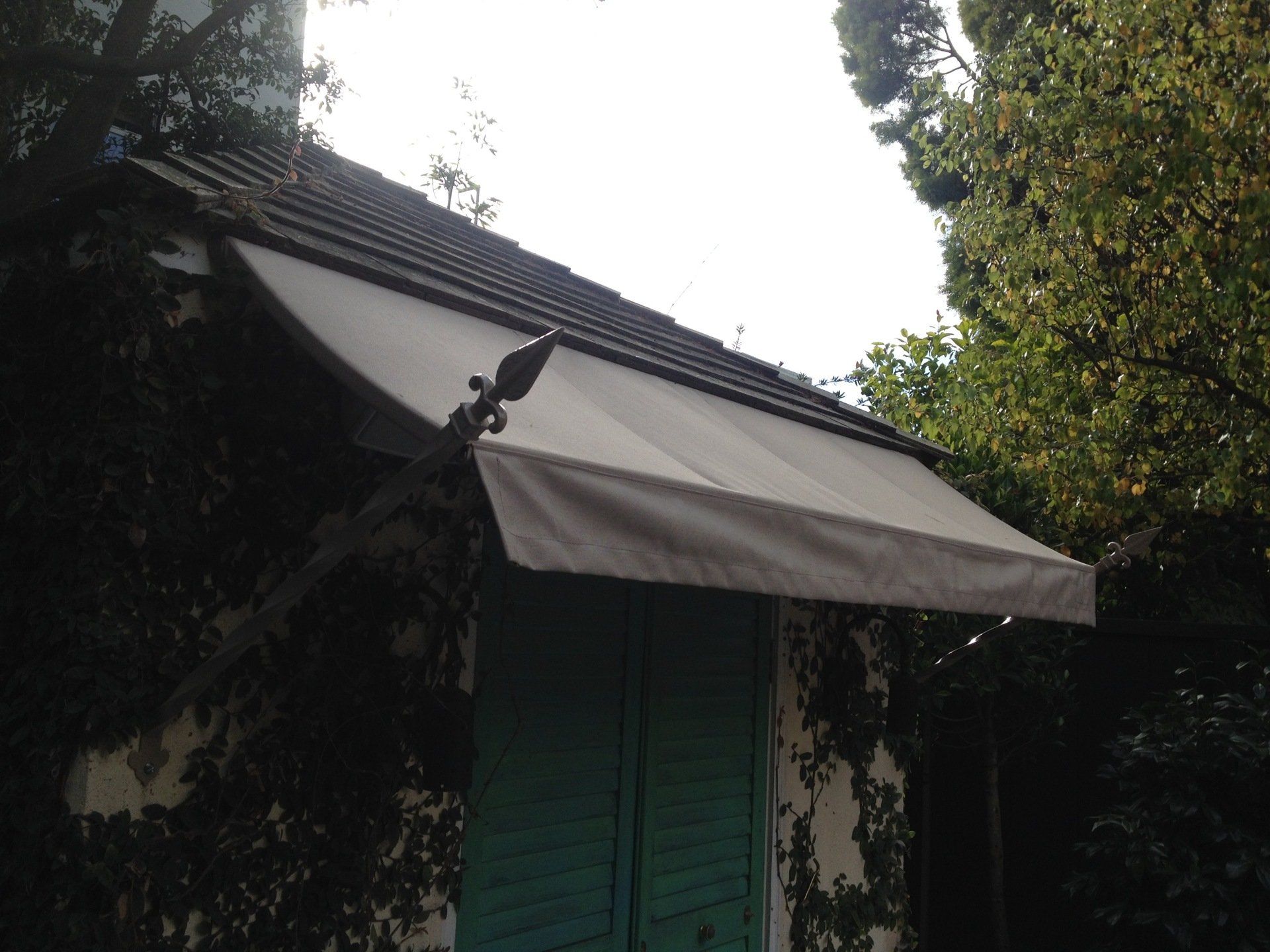 A white awning is hanging over a door with green shutters