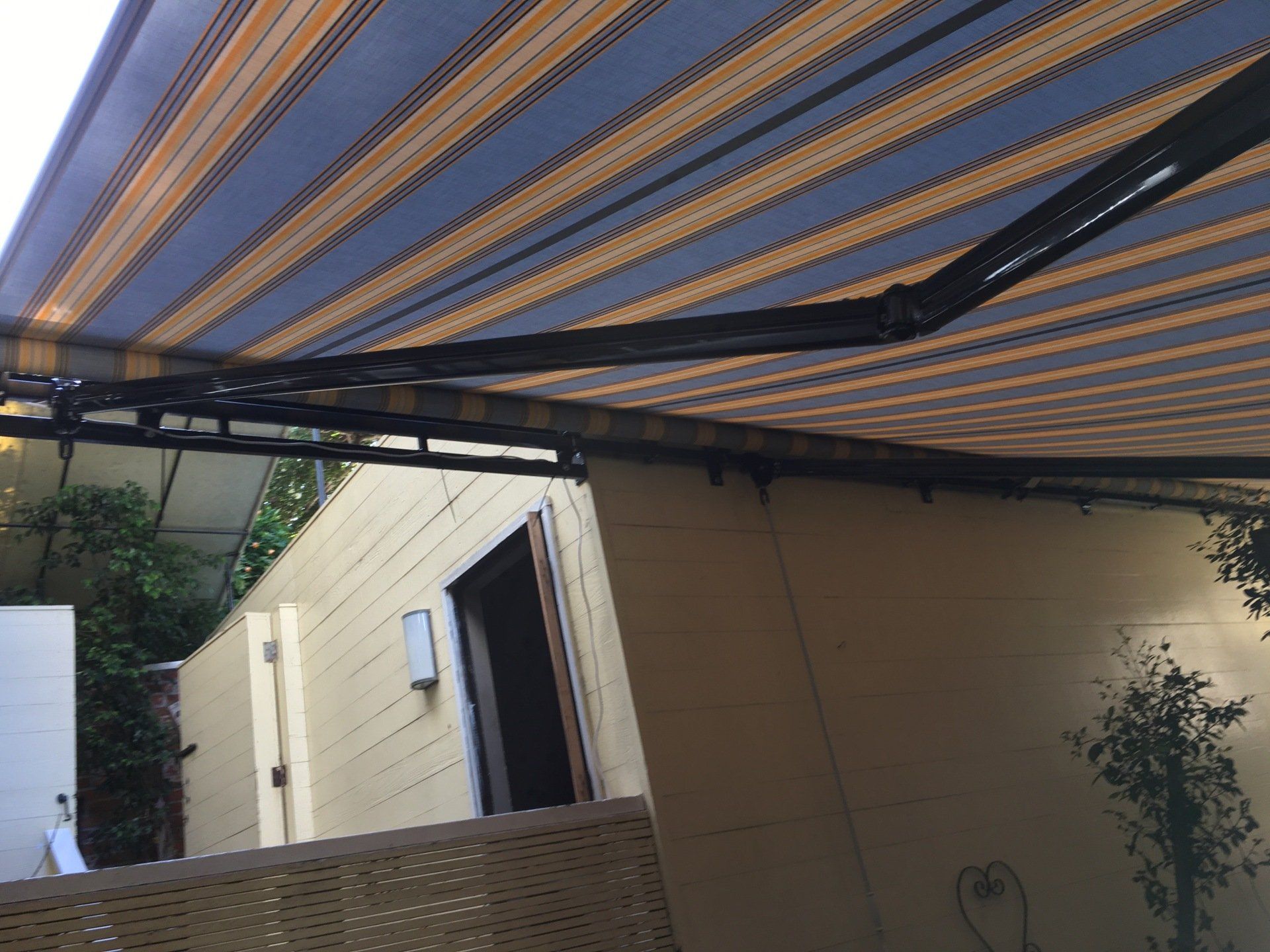A blue and yellow striped awning is hanging over a patio