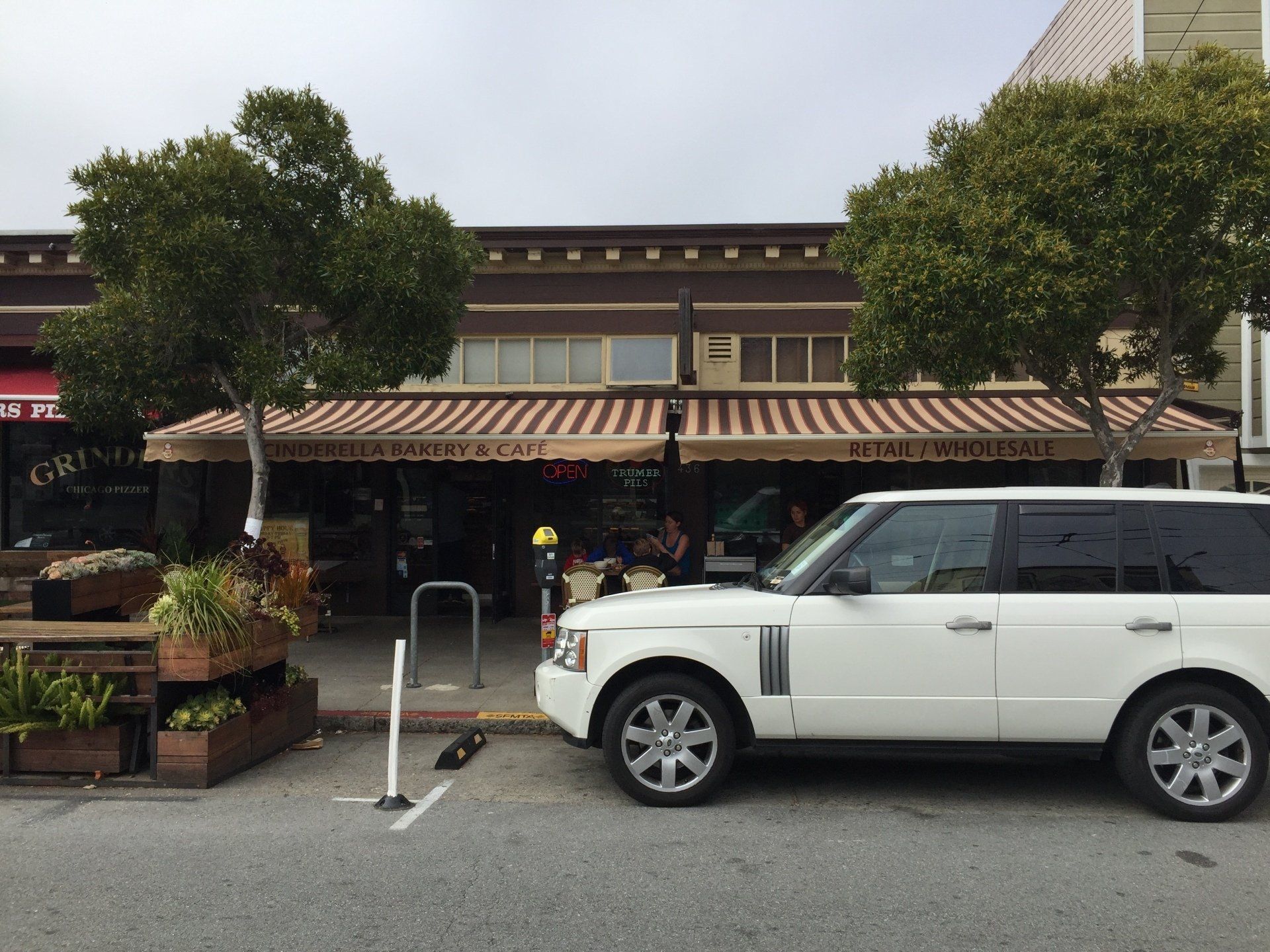 A white range rover is parked in front of a restaurant