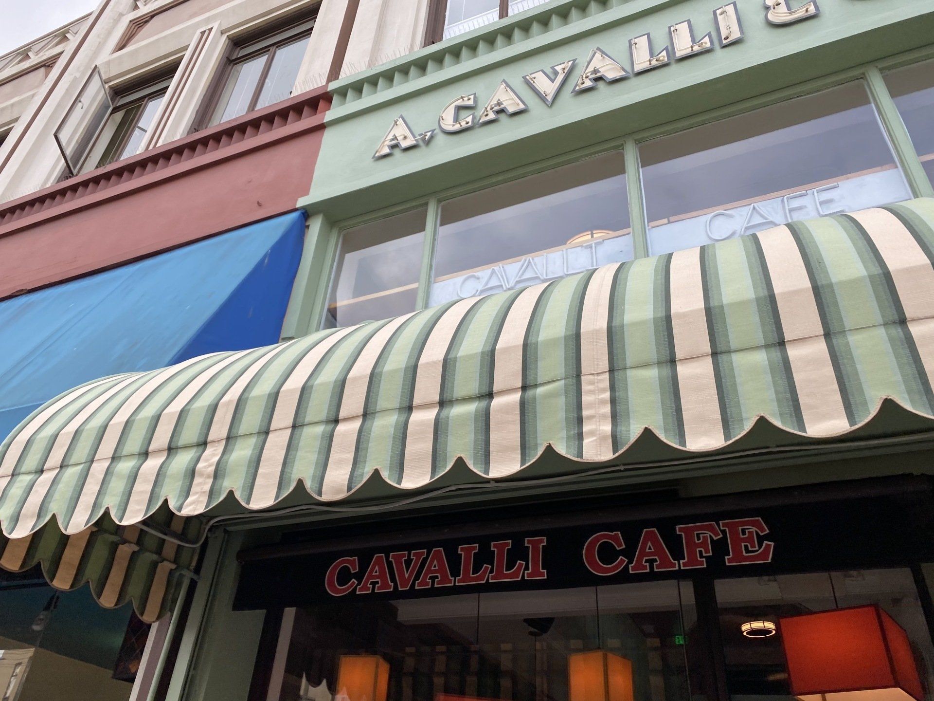 The cavalli cafe has a striped awning over the entrance