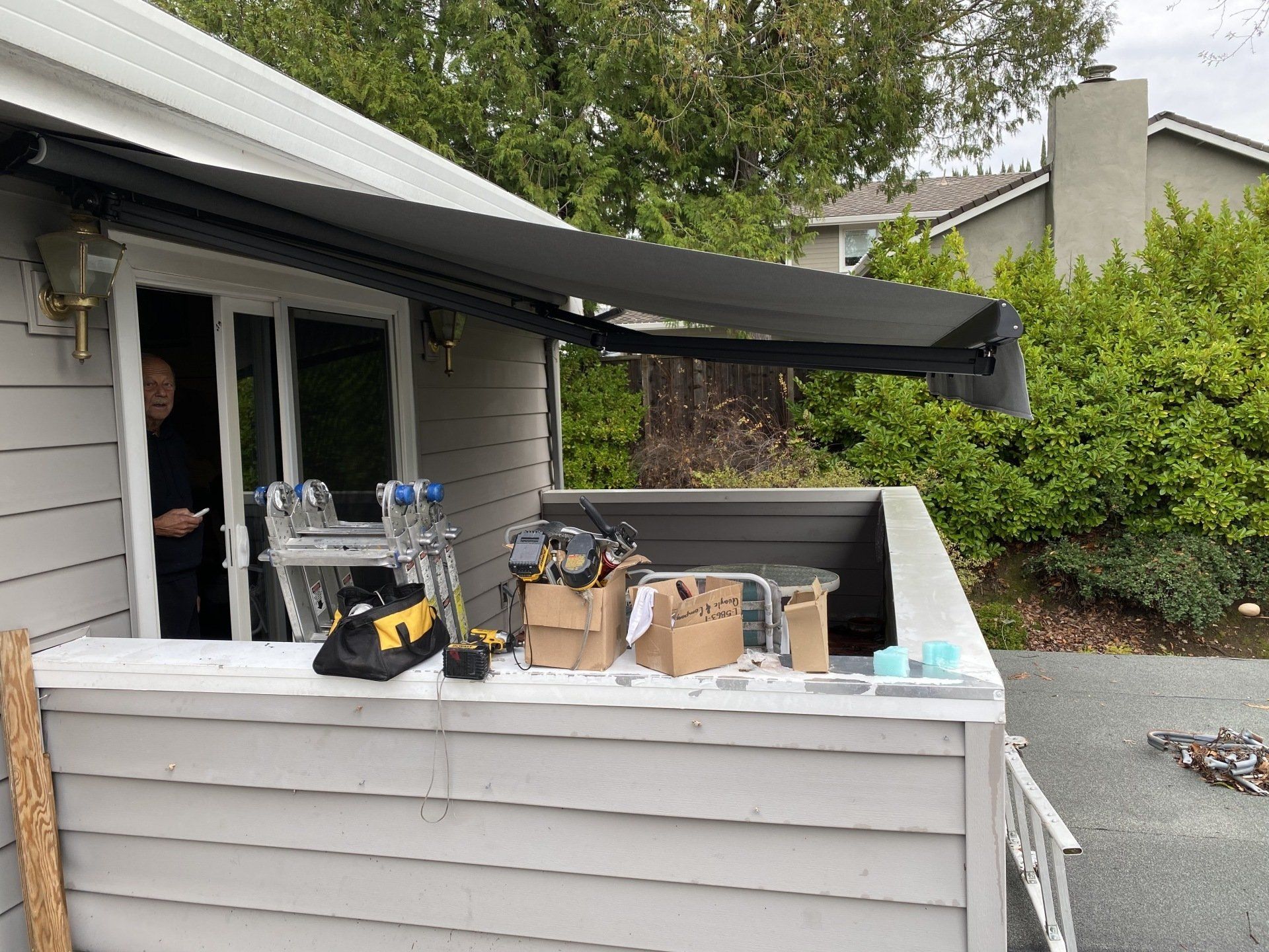 A man is standing in front of a house with an awning on it.