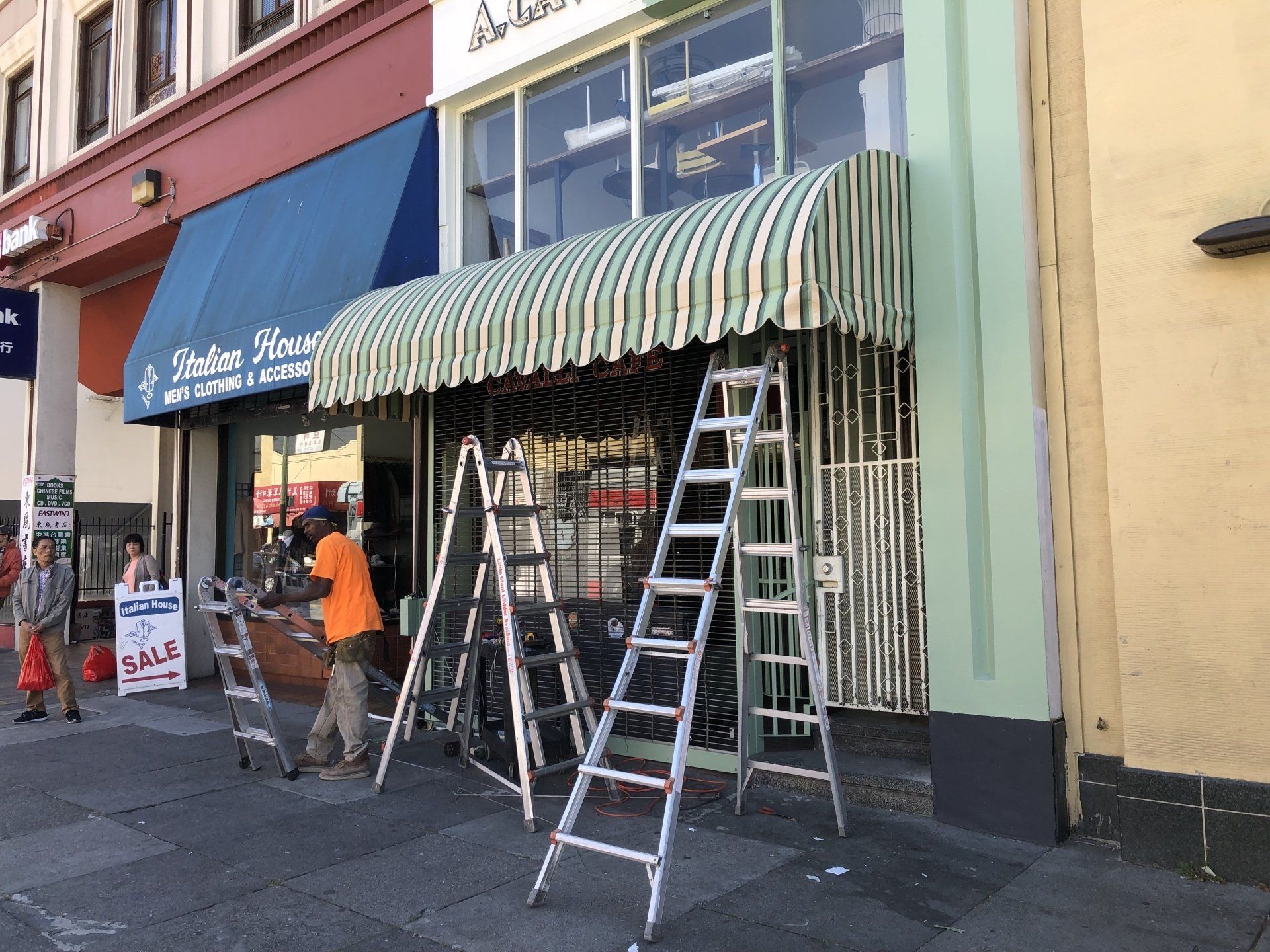 A man is standing on a ladder in front of a store.