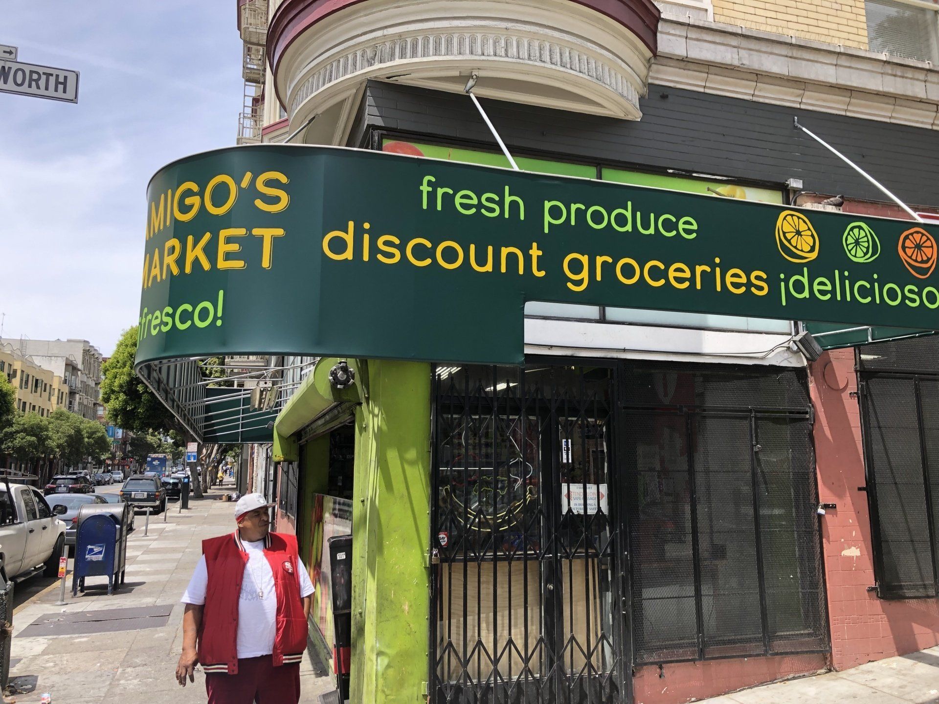 A man is standing in front of a store that sells fresh produce discount groceries