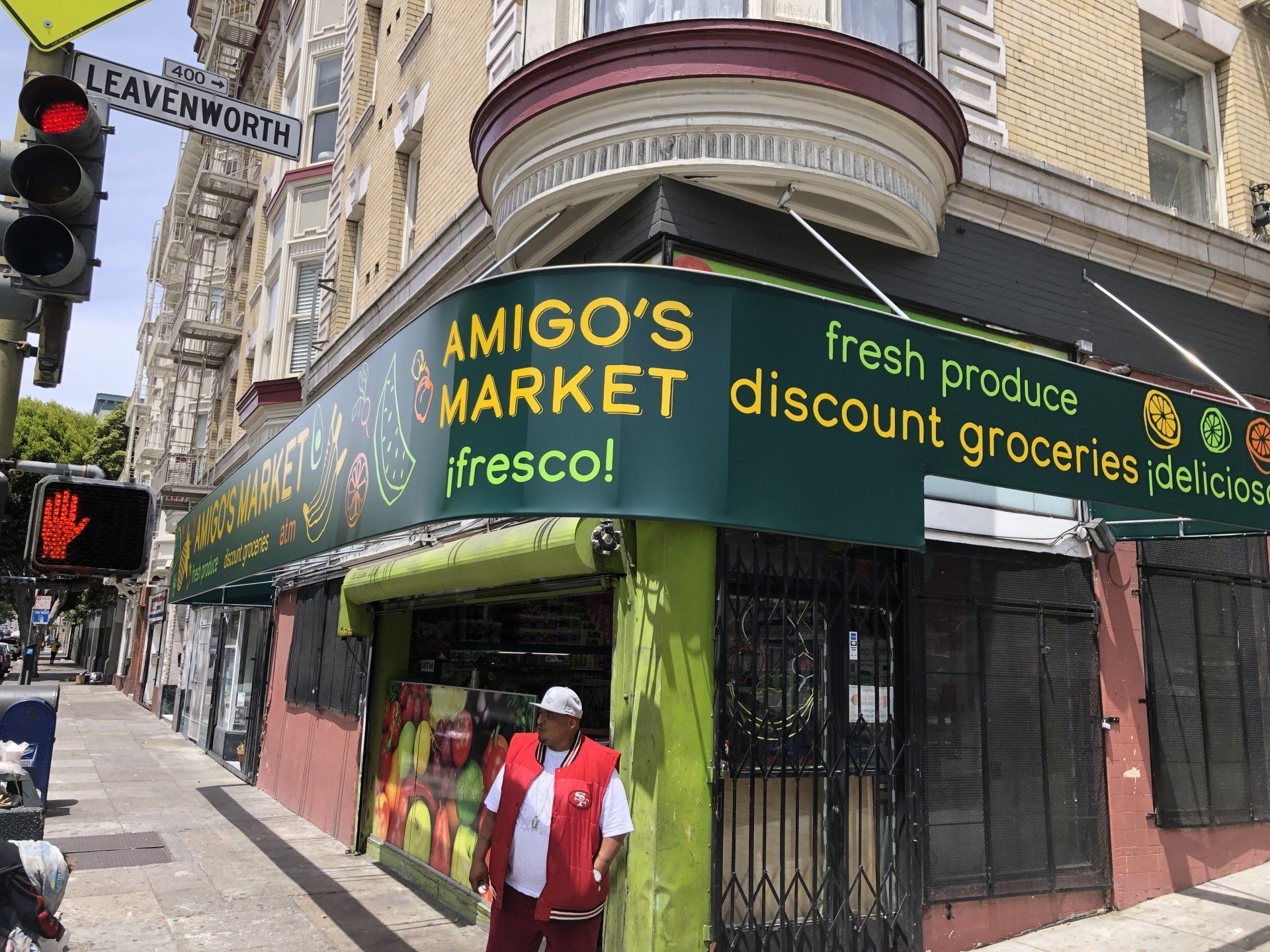 A man in a red vest is standing in front of amigo 's market