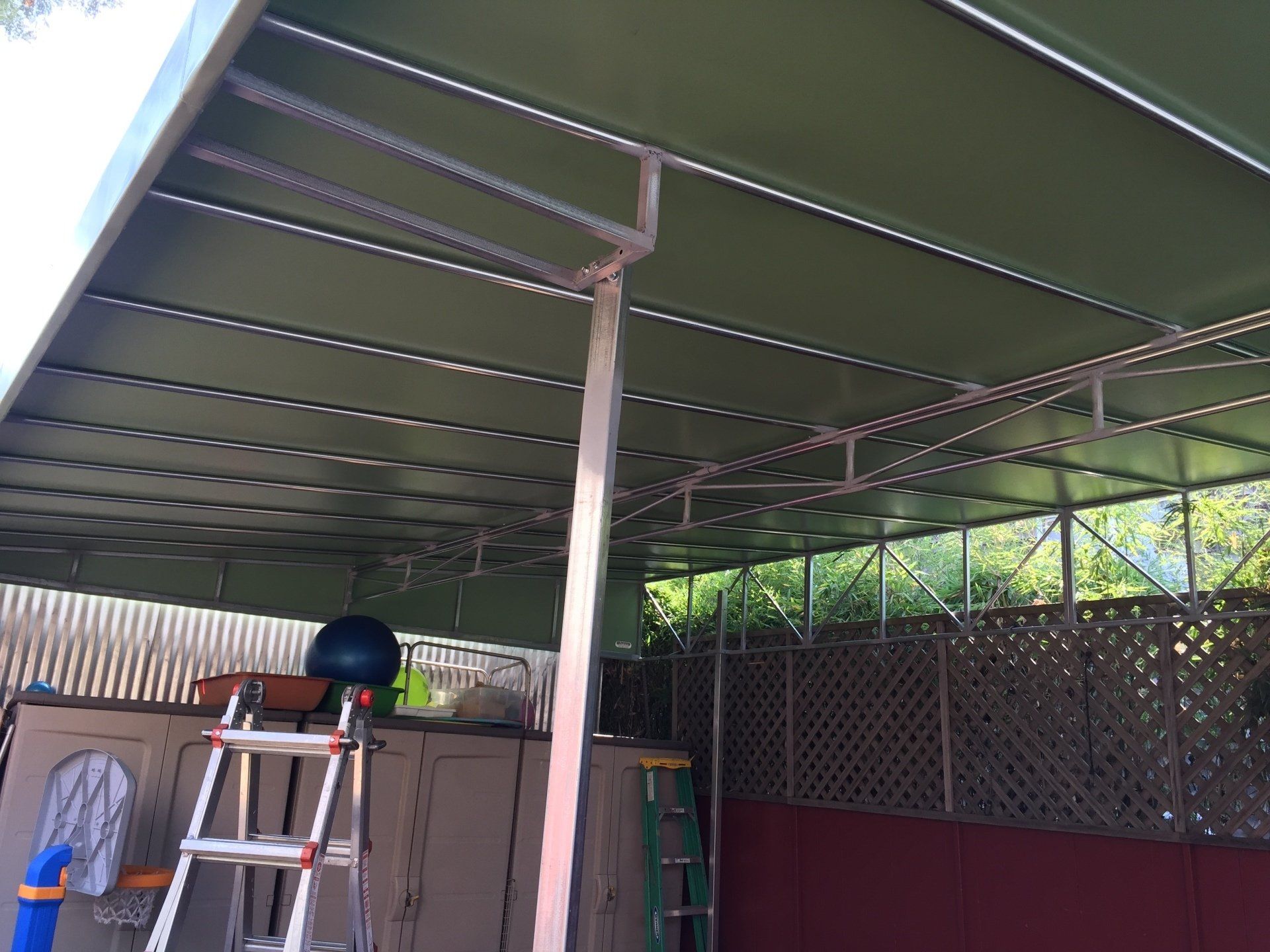 A ladder is sitting under a canopy in a backyard