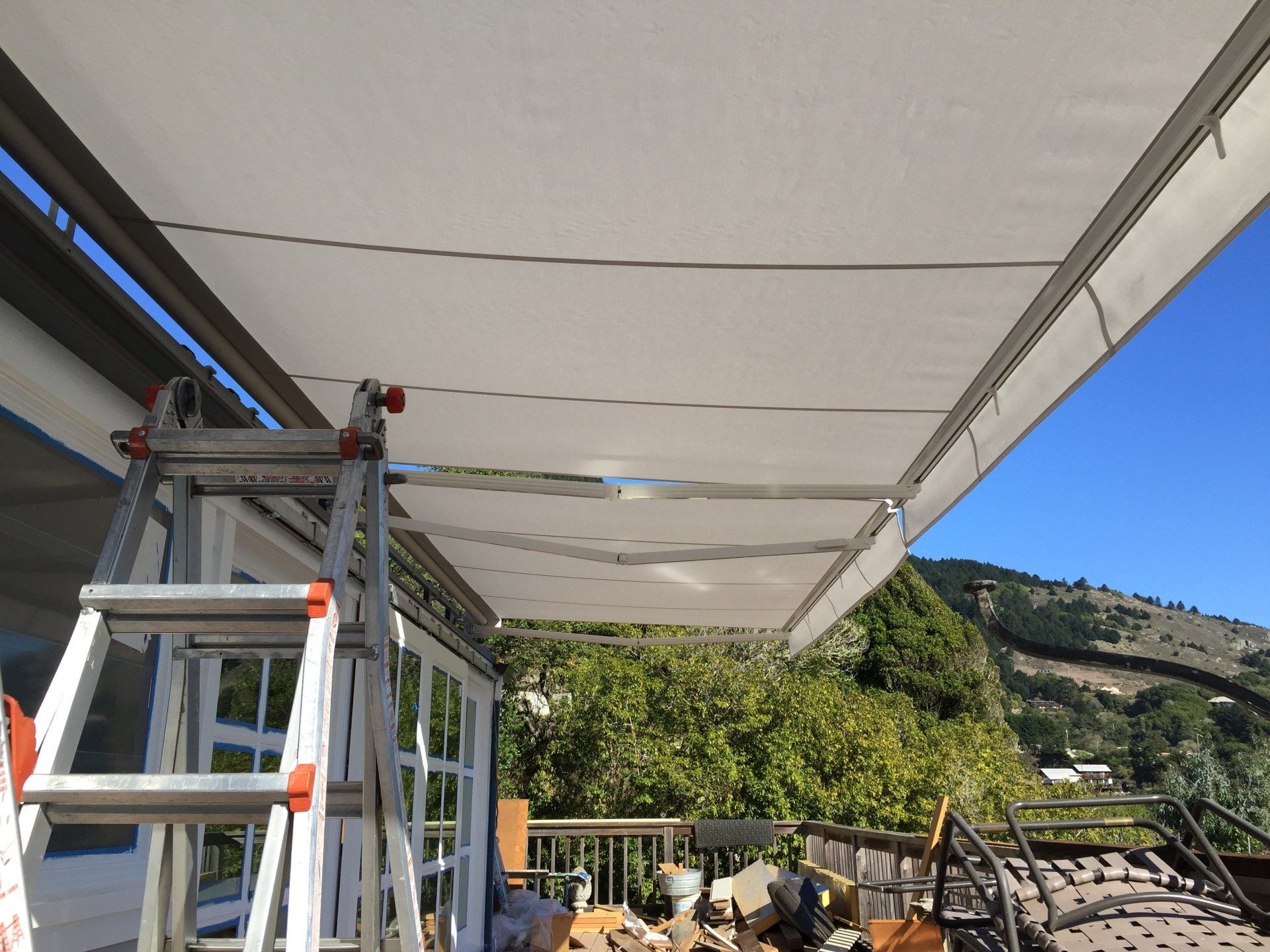 A ladder is sitting under an awning on a balcony.