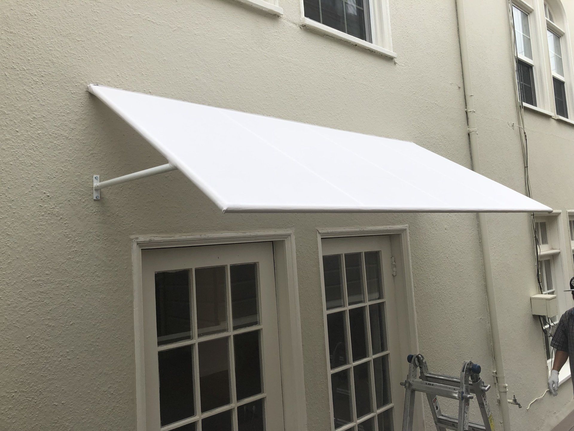 A white awning is hanging over a window on the side of a building.
