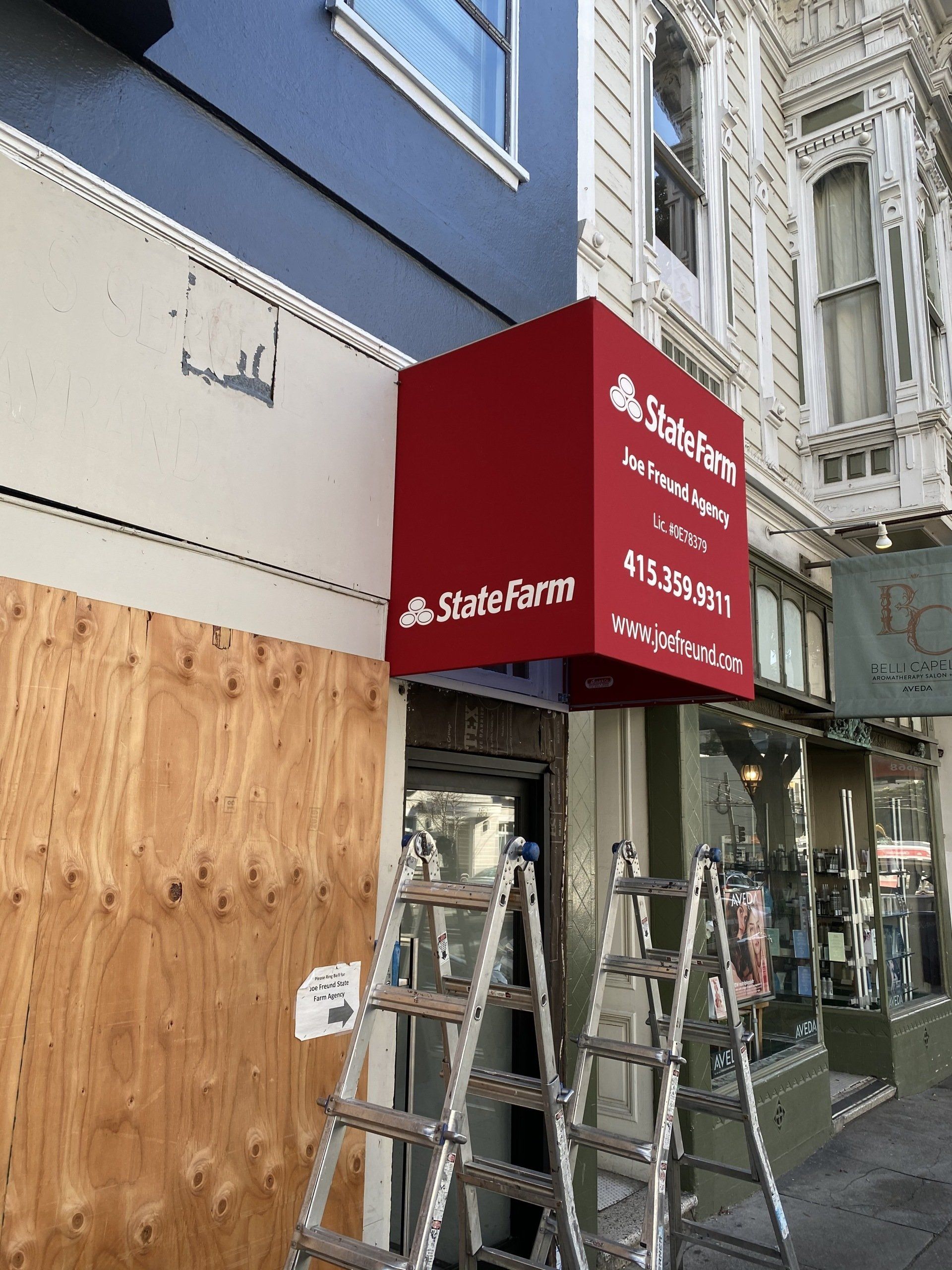 A red awning is being installed on the side of a building.