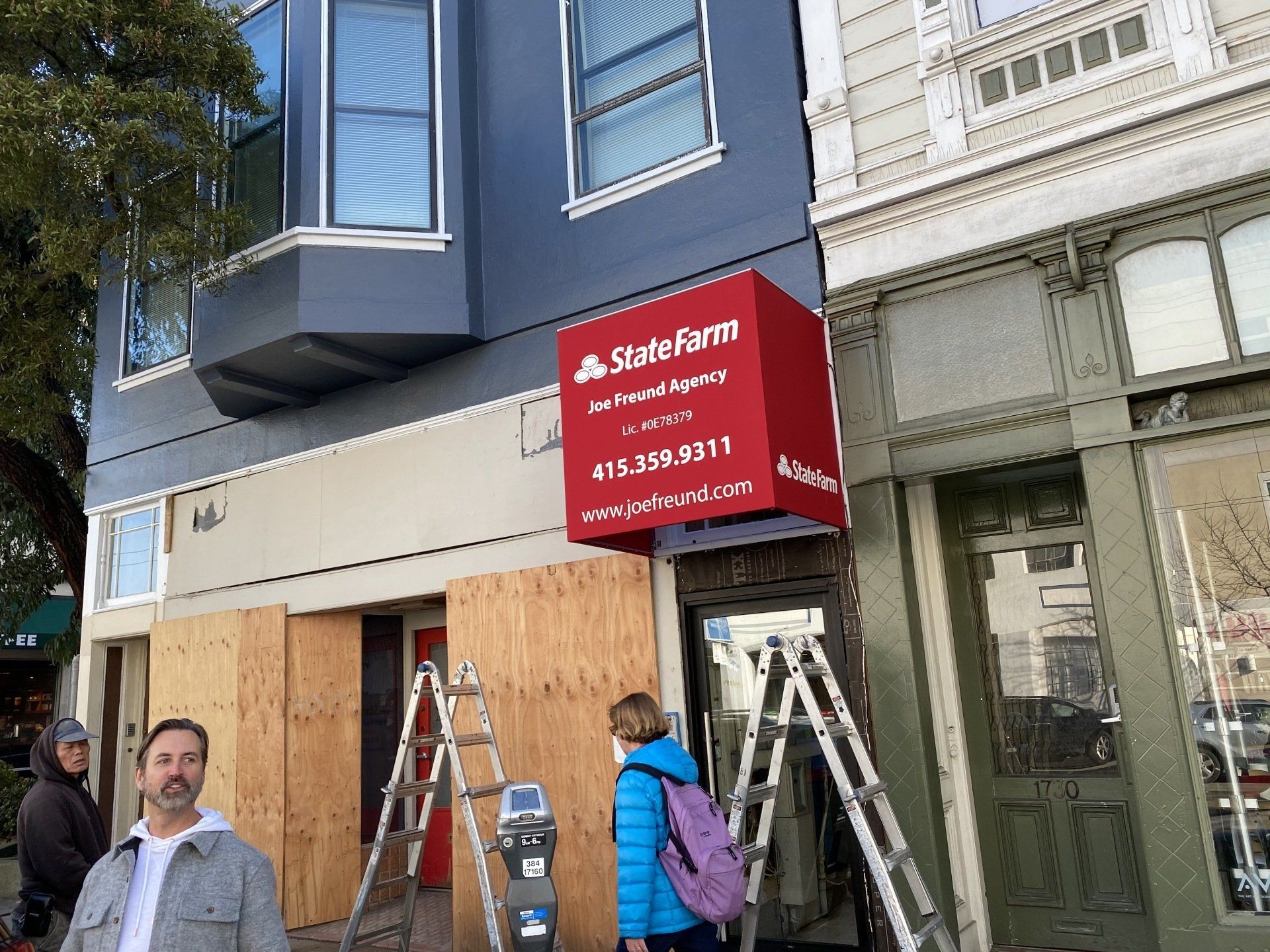 A man and a woman are standing in front of a building that is being boarded up.