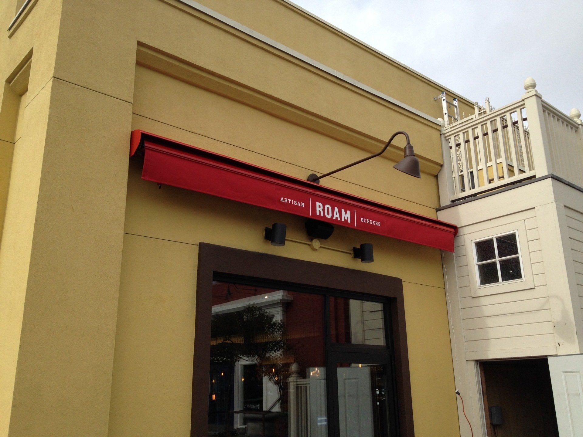 A yellow building with a red awning that says adam