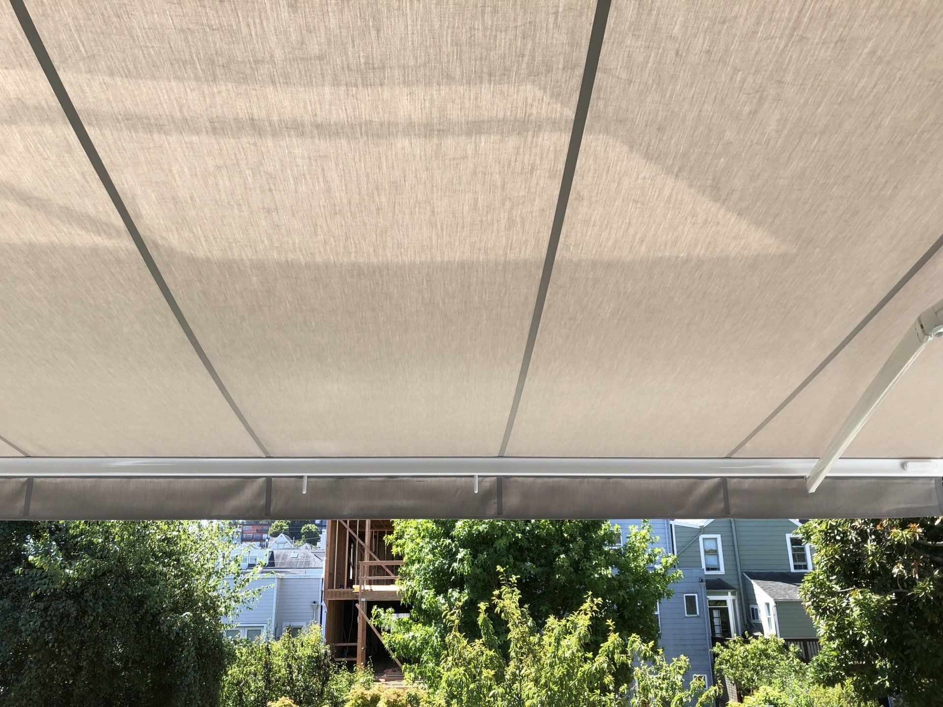 A white awning is covering a balcony with trees in the background
