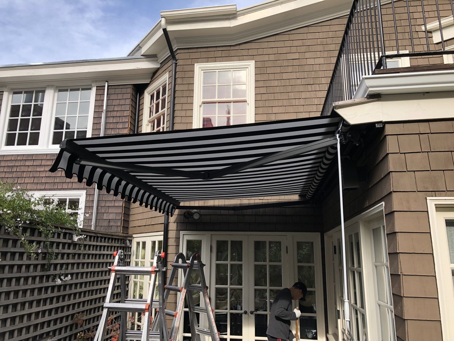A man is standing under a canopy on the side of a house.