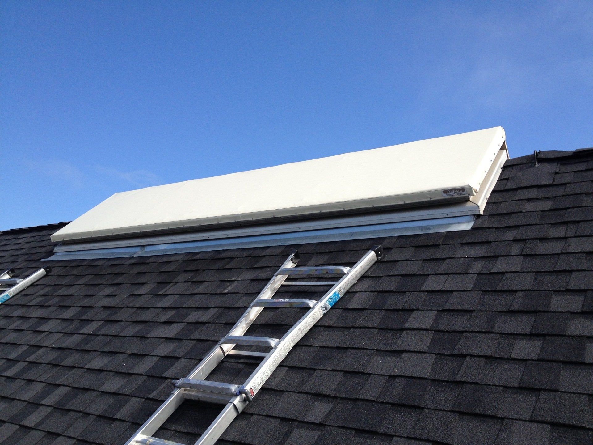 A ladder is sitting on top of a roof next to a solar panel.