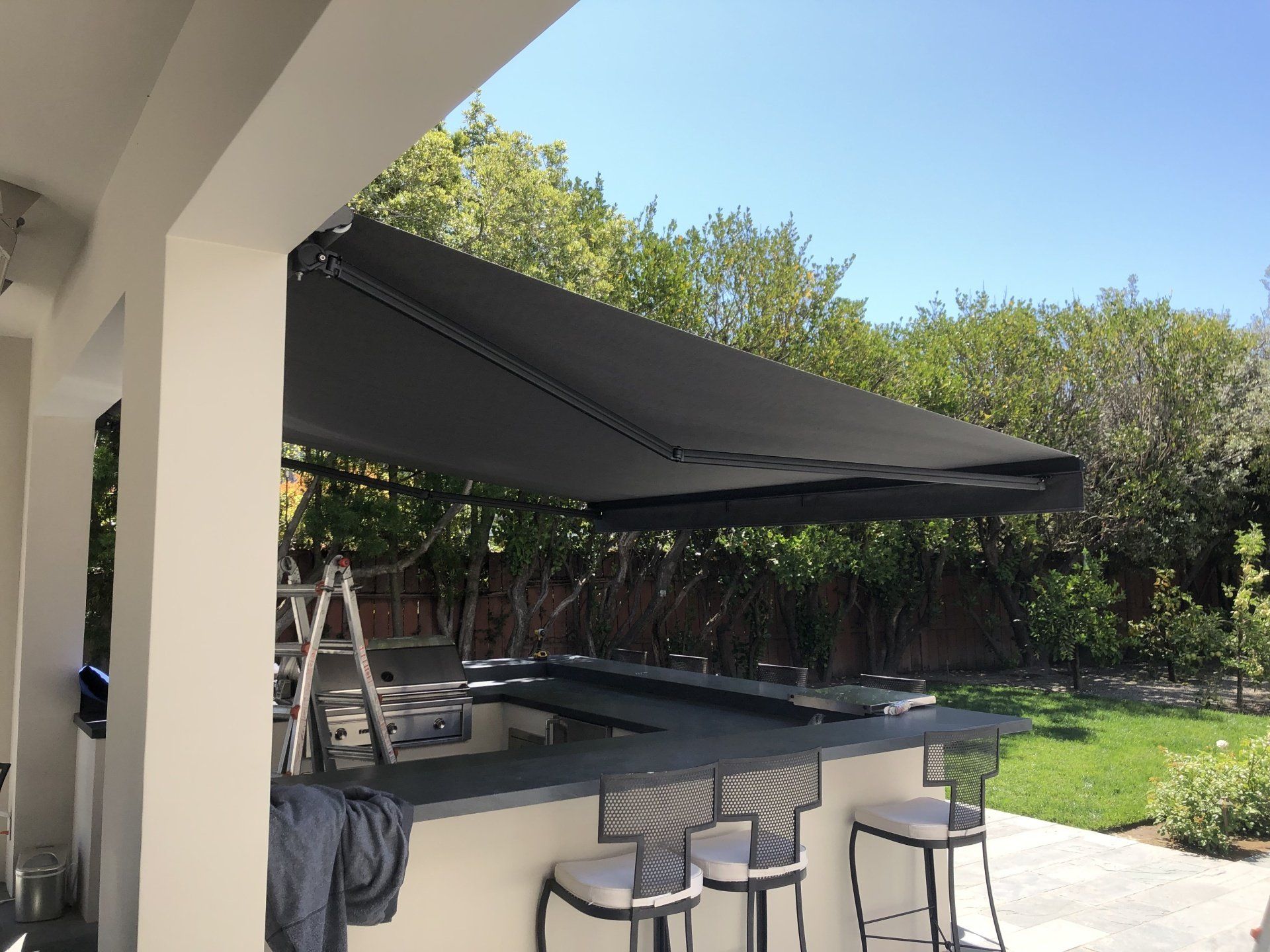 A patio with a black awning over a table and chairs.
