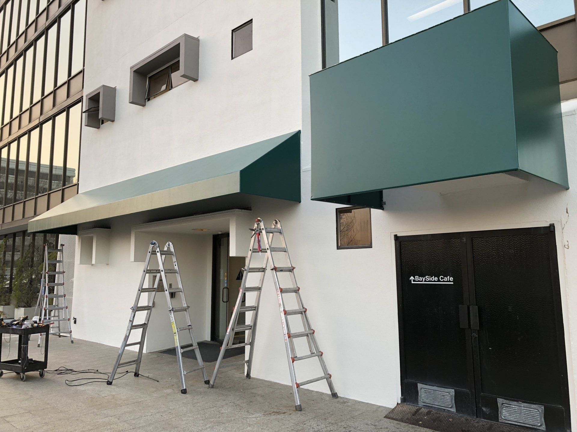 A green awning is being installed on the side of a building