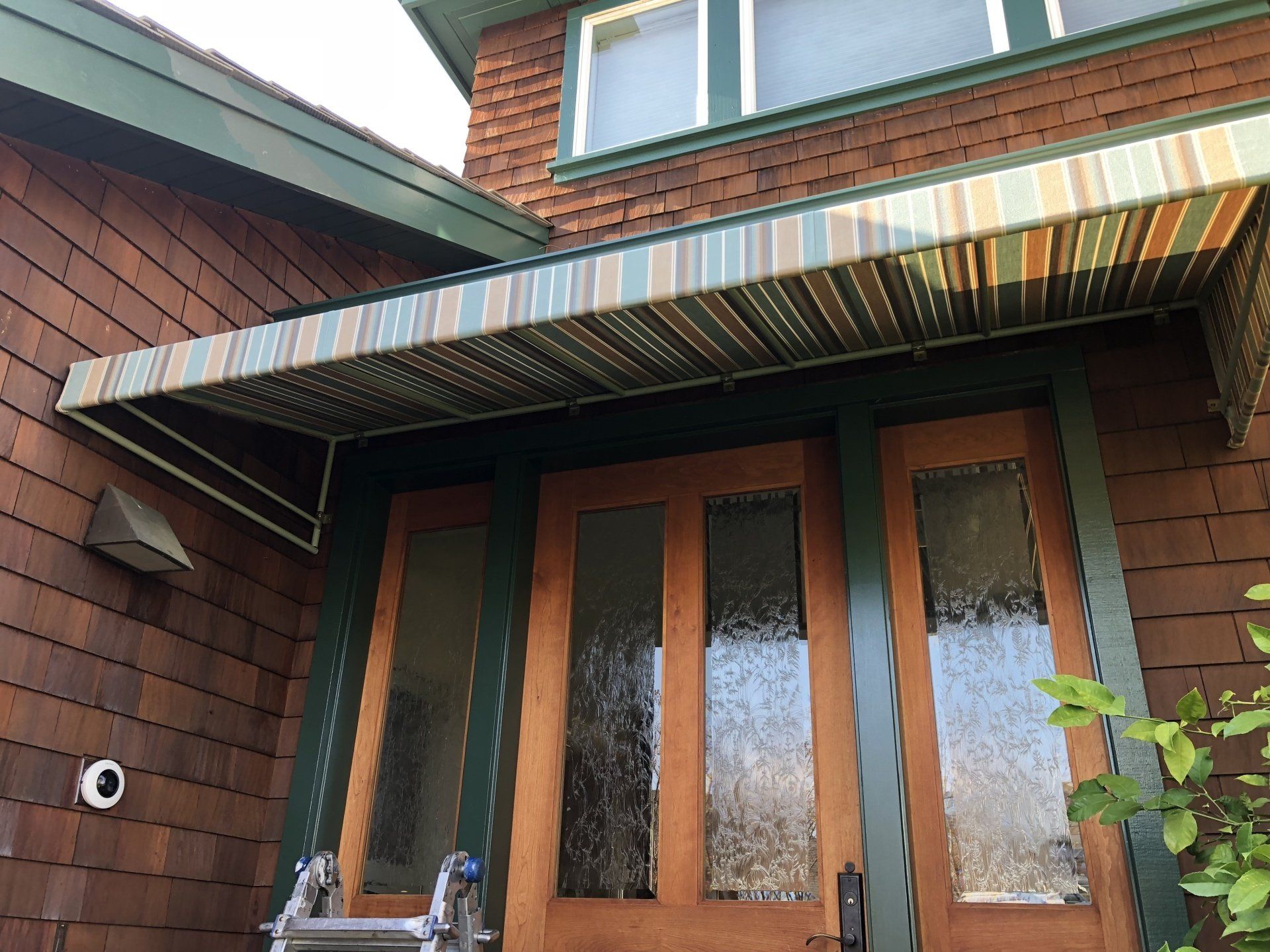 A house with a striped awning over the front door.
