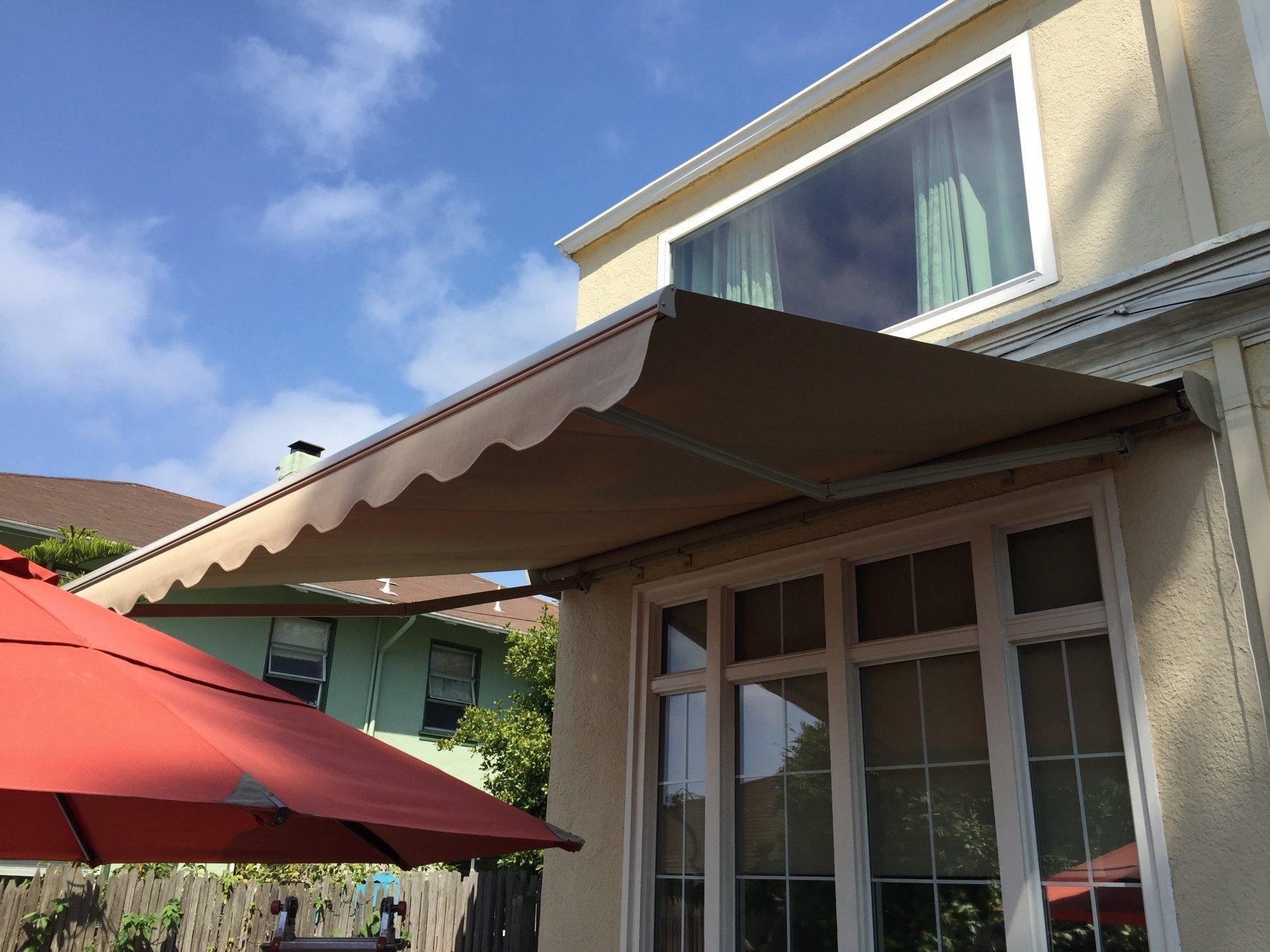 A house with an awning and a red umbrella