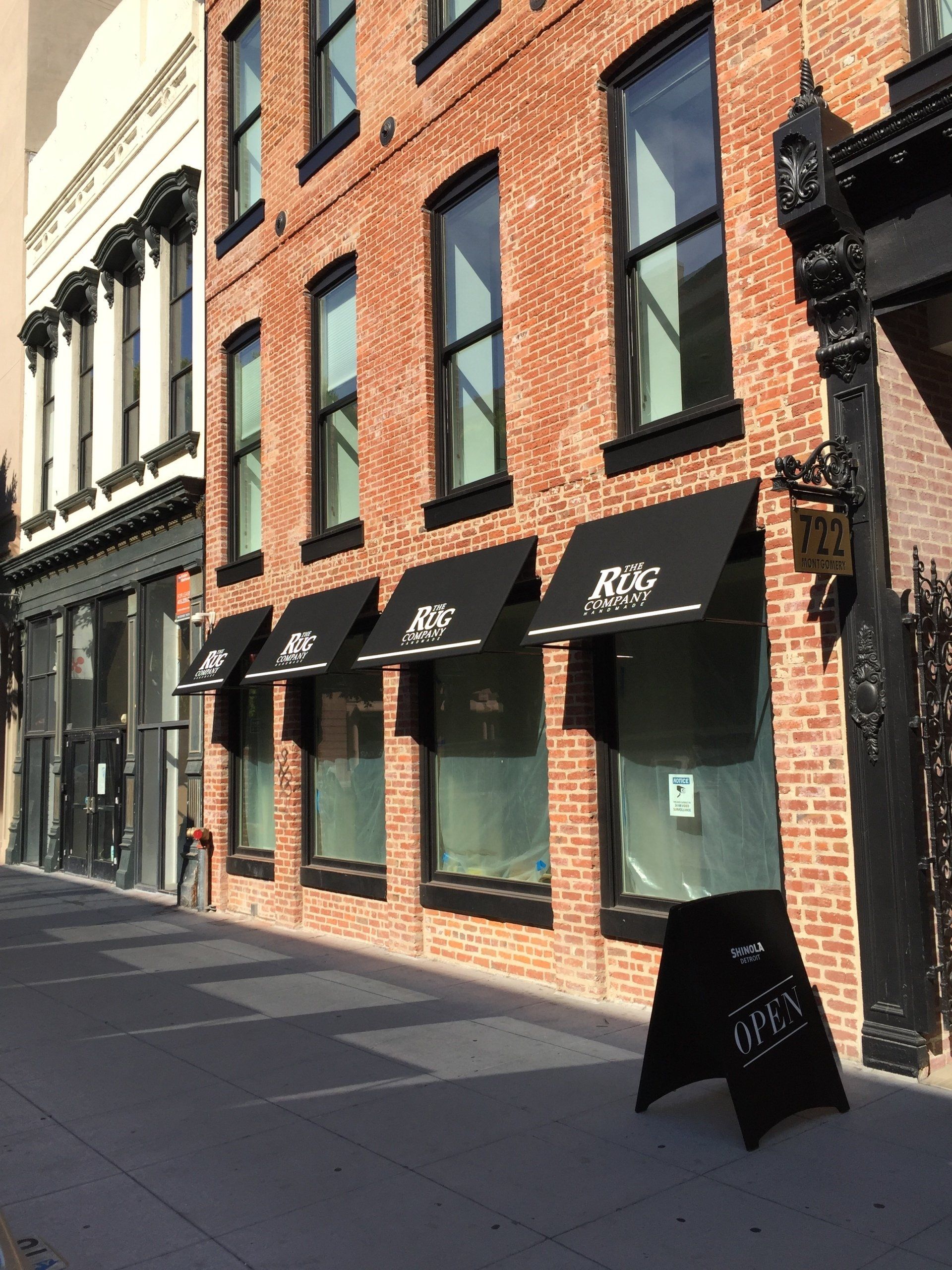 A brick building with black awnings and a sign that says open