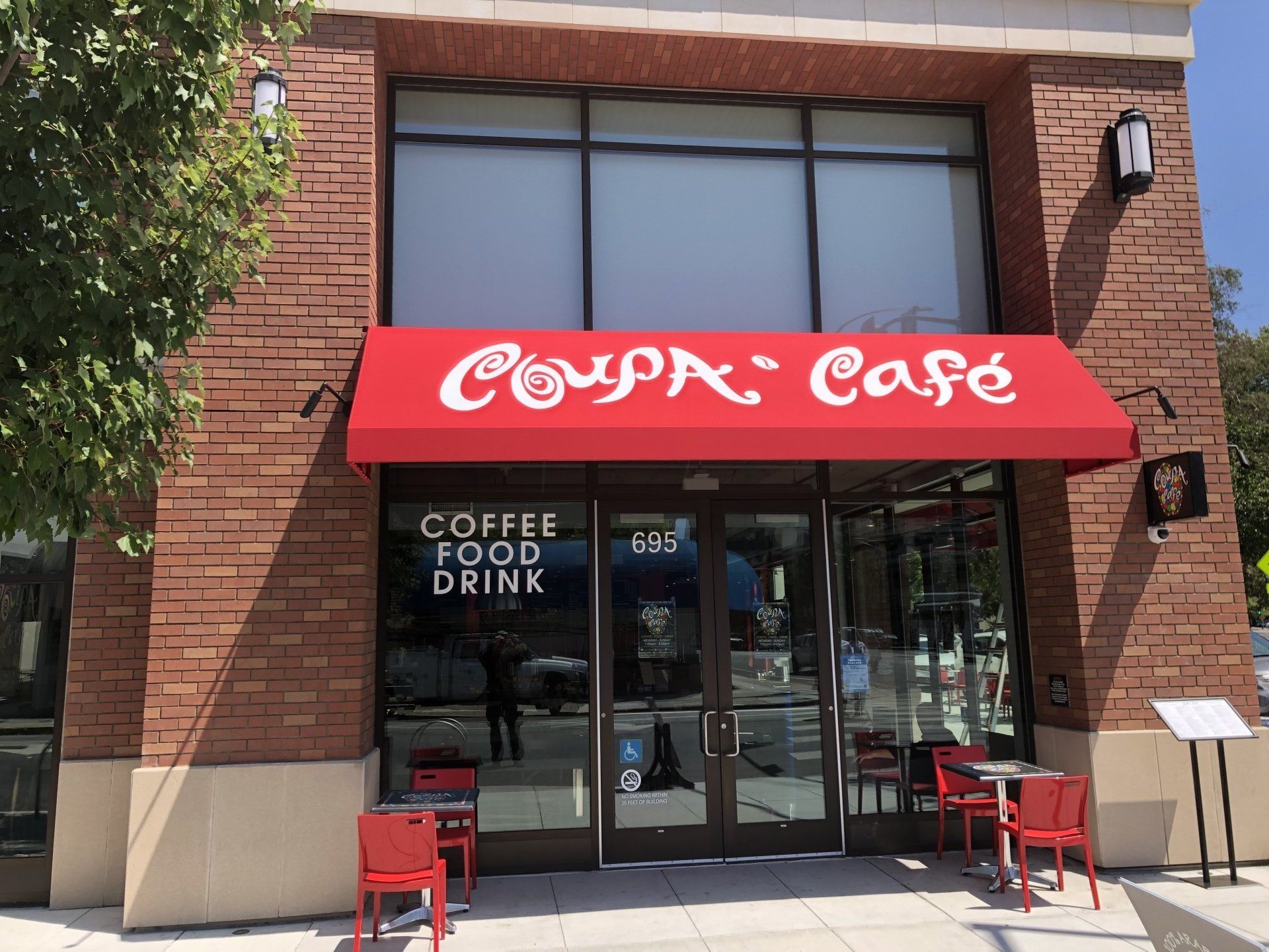 A cafe with a red awning that says coffee food drink