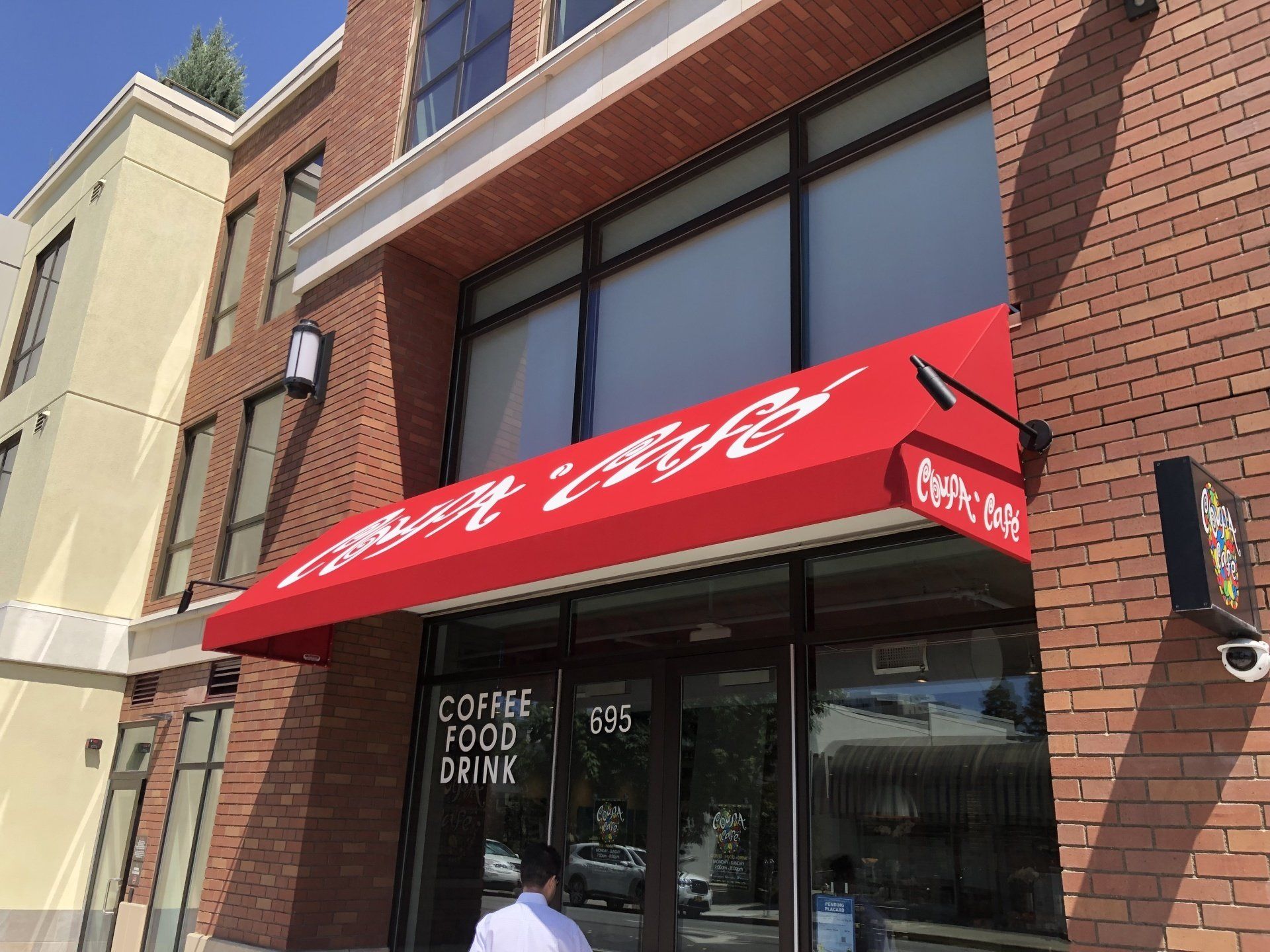 A brick building with a red awning that says coffee food drink