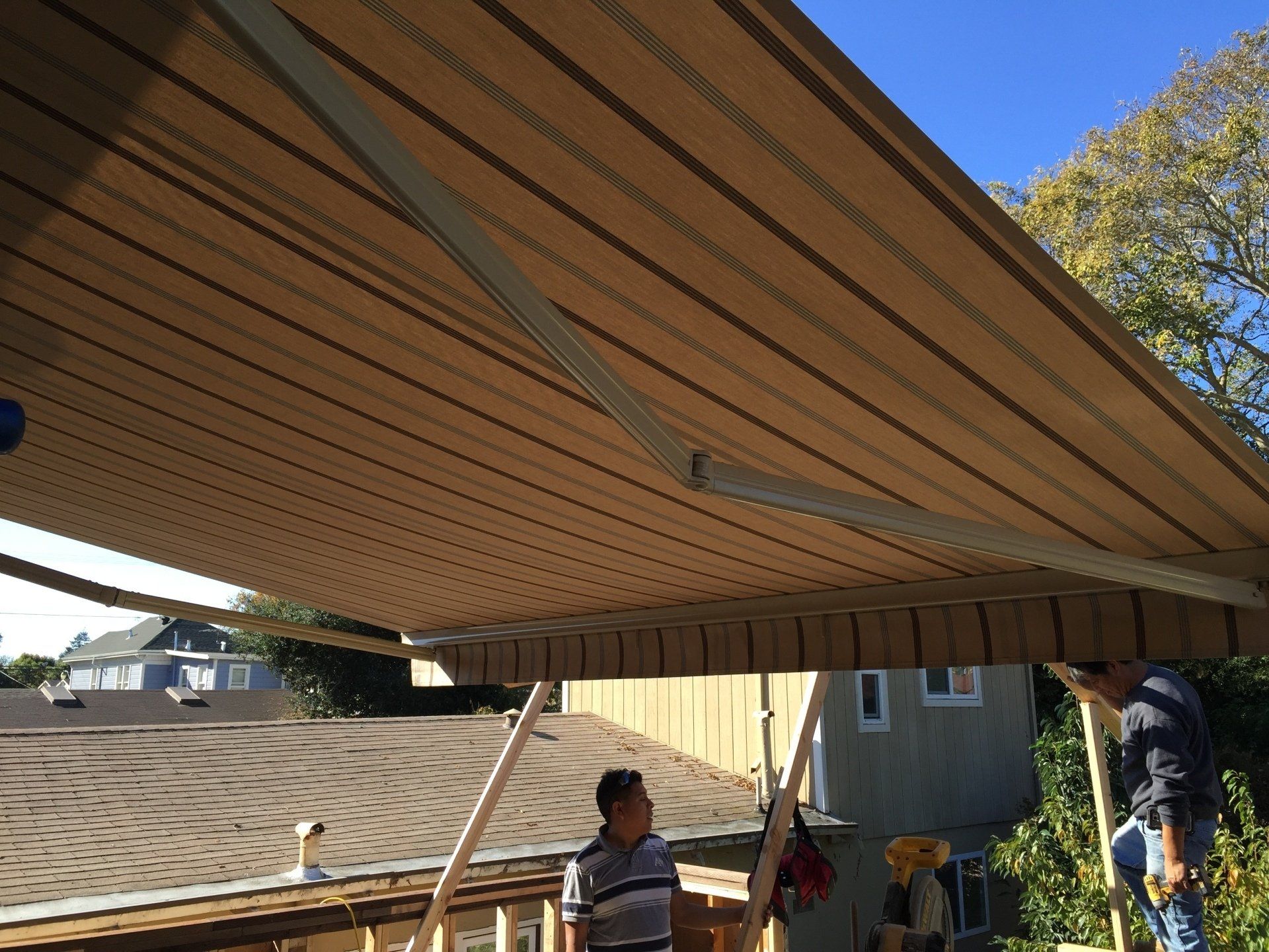 A man is standing under an awning on the roof of a house