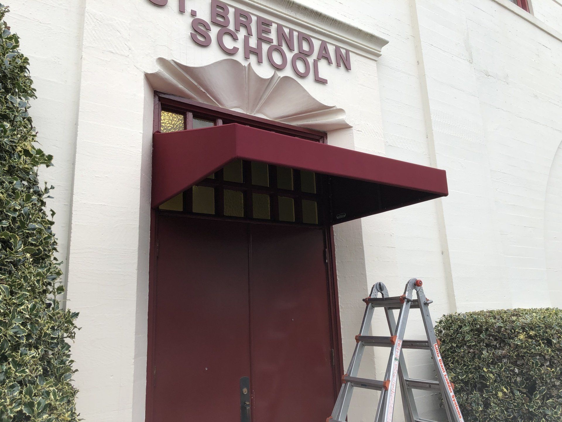 A red awning on the front of a building that says brendan school