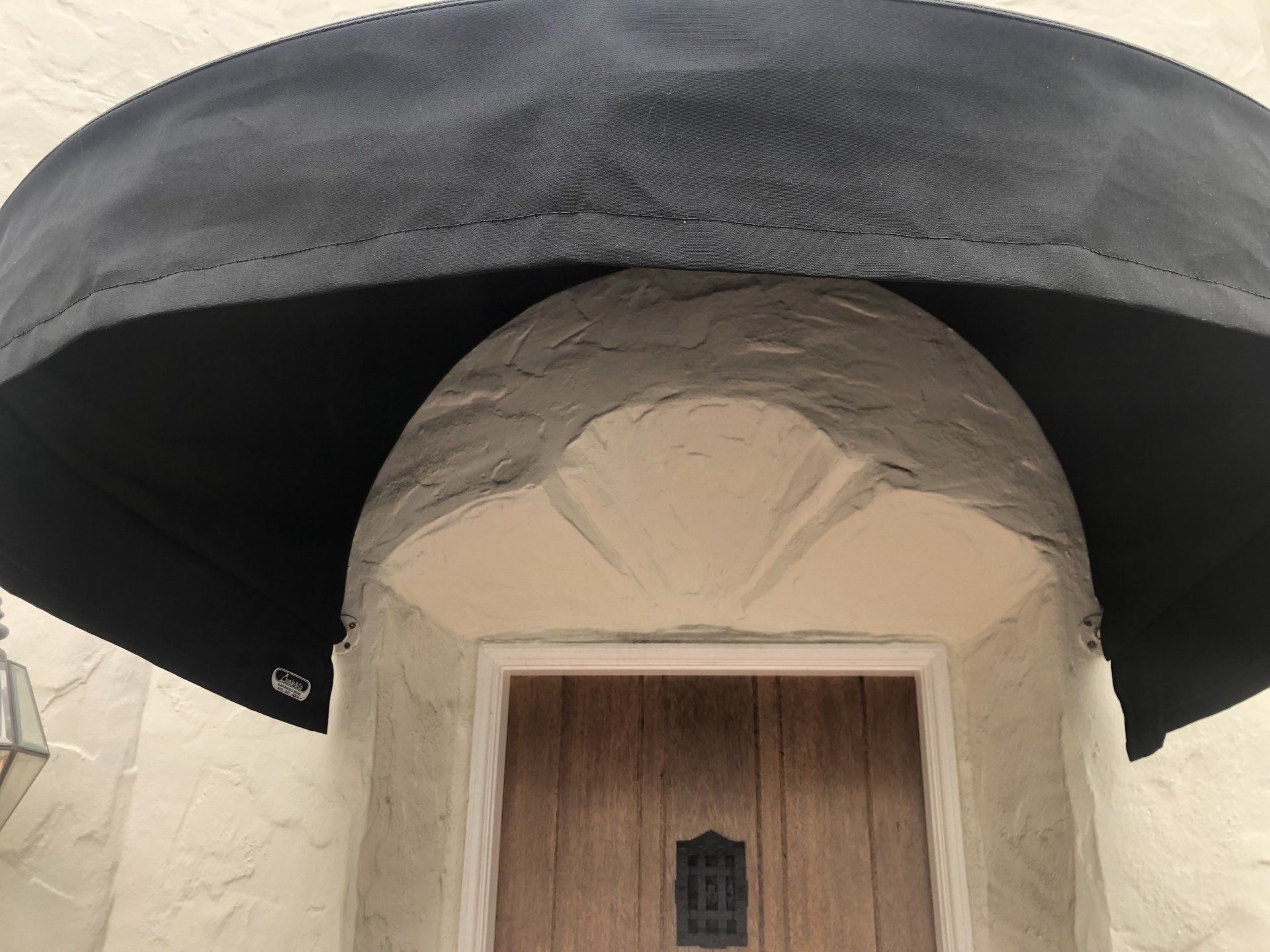 A wooden door with a black awning over it