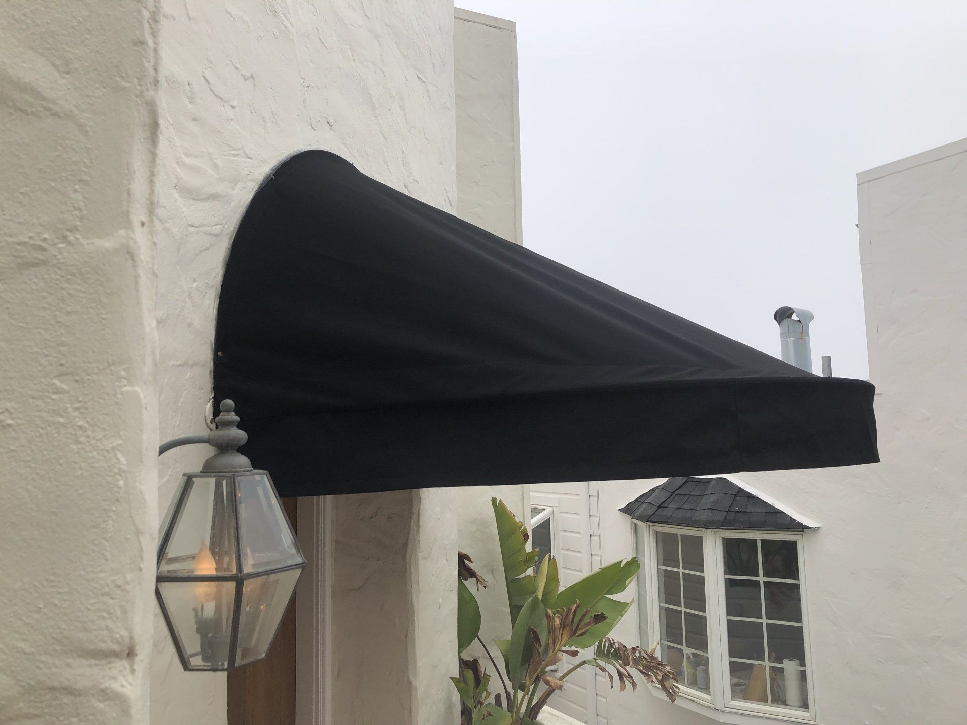 A black awning is on the side of a white building