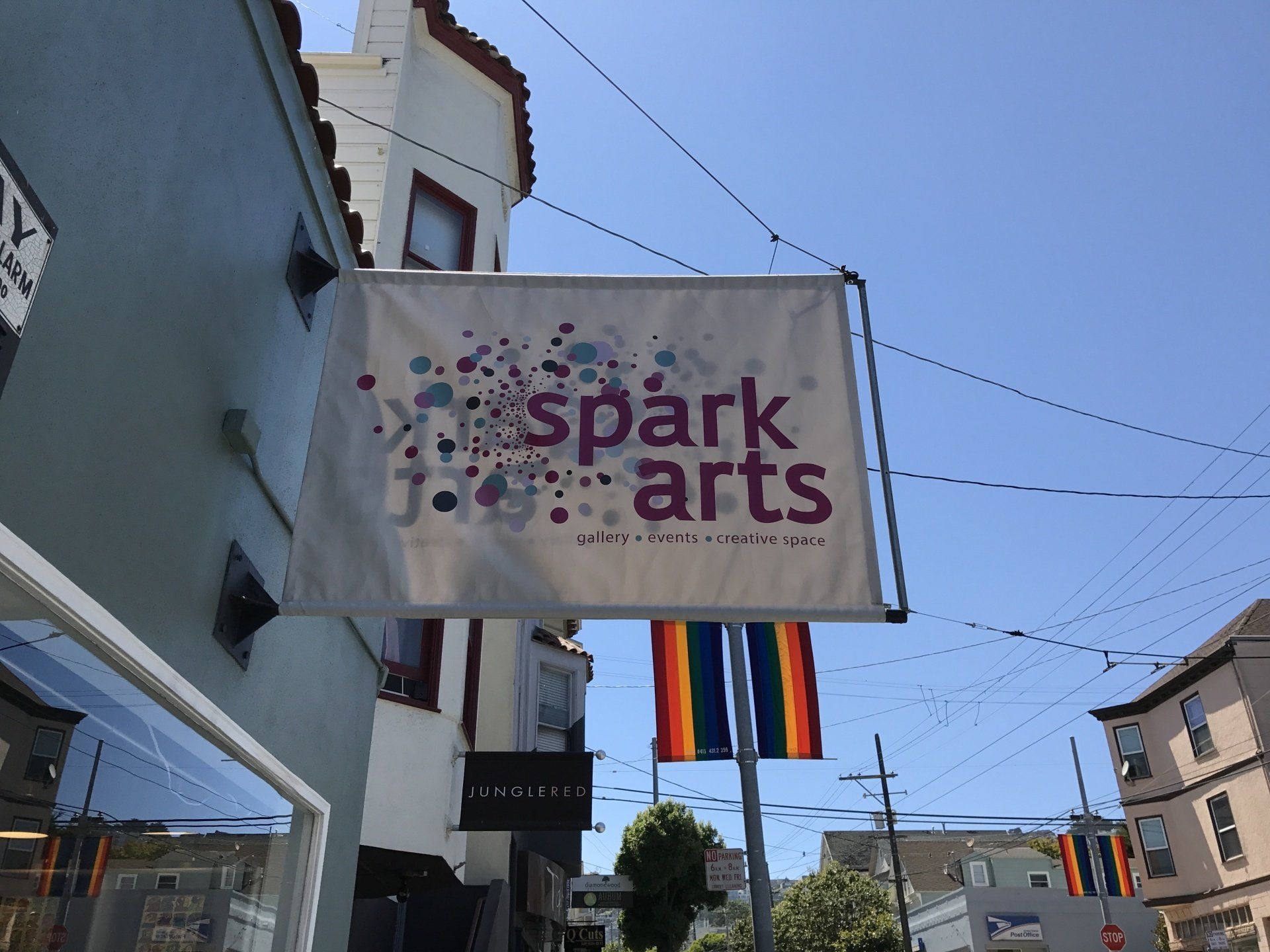 A sign for spark arts hangs outside of a building