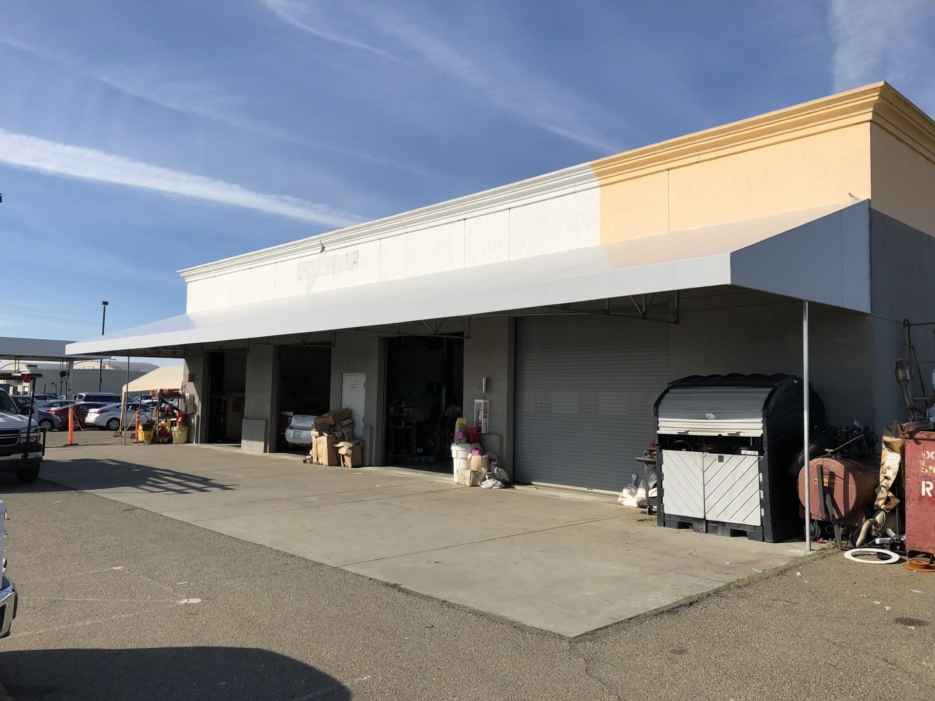 A car is parked in front of a building with a canopy over it.