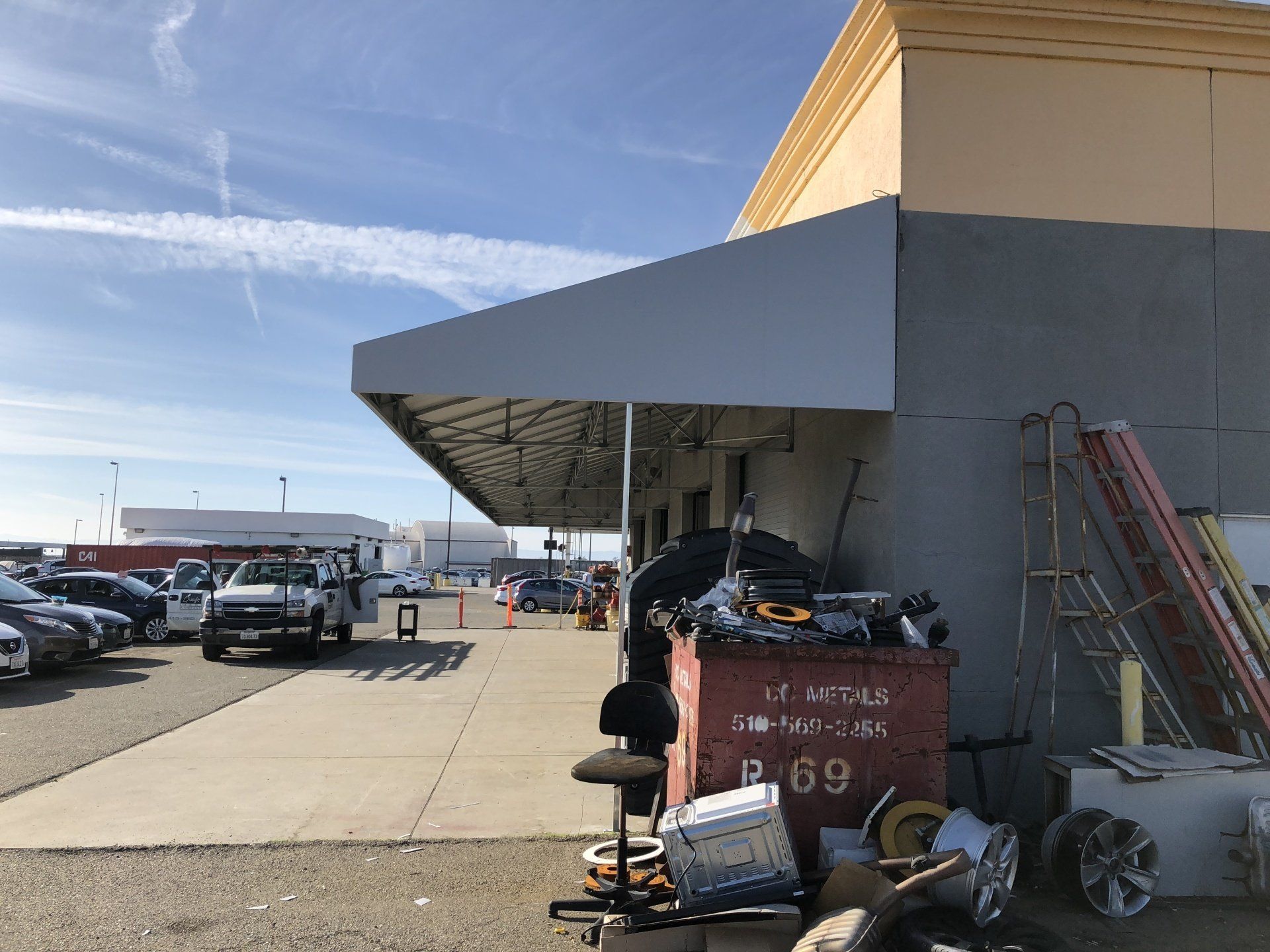 A large trash can is sitting in front of a building.
