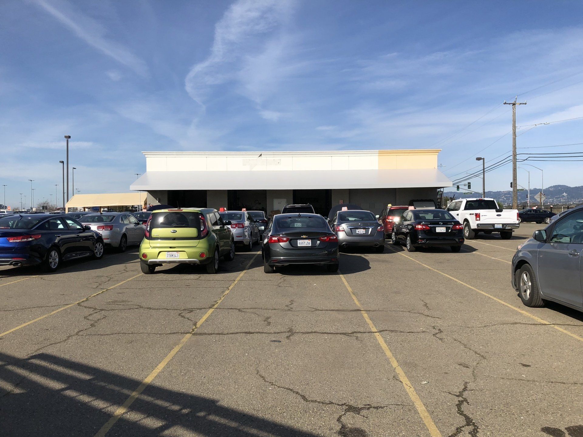 A lot of cars are parked in a parking lot in front of a building.
