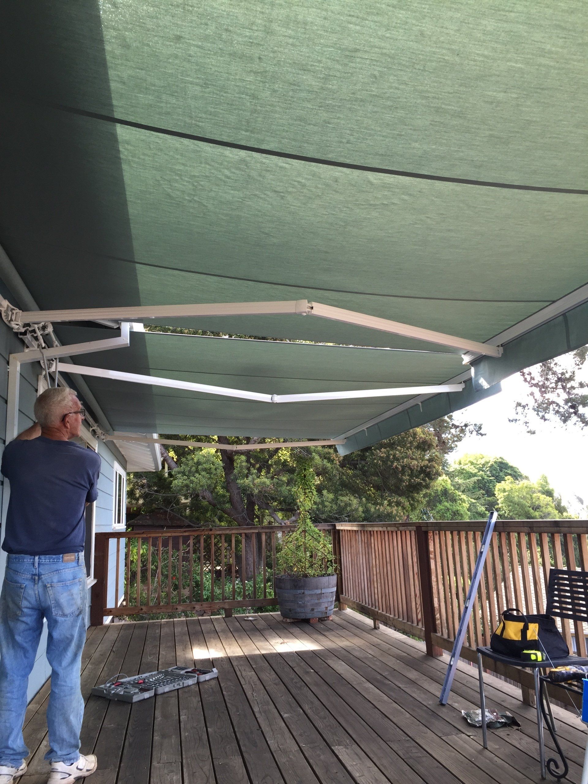 A man is standing on a deck under an awning