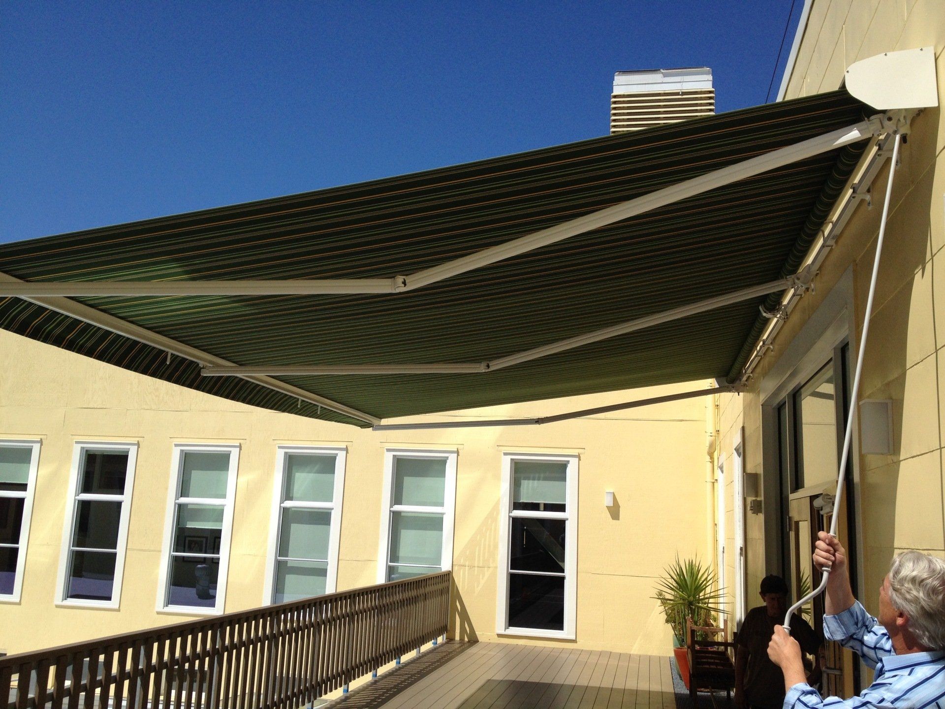A man is adjusting an awning on the side of a building