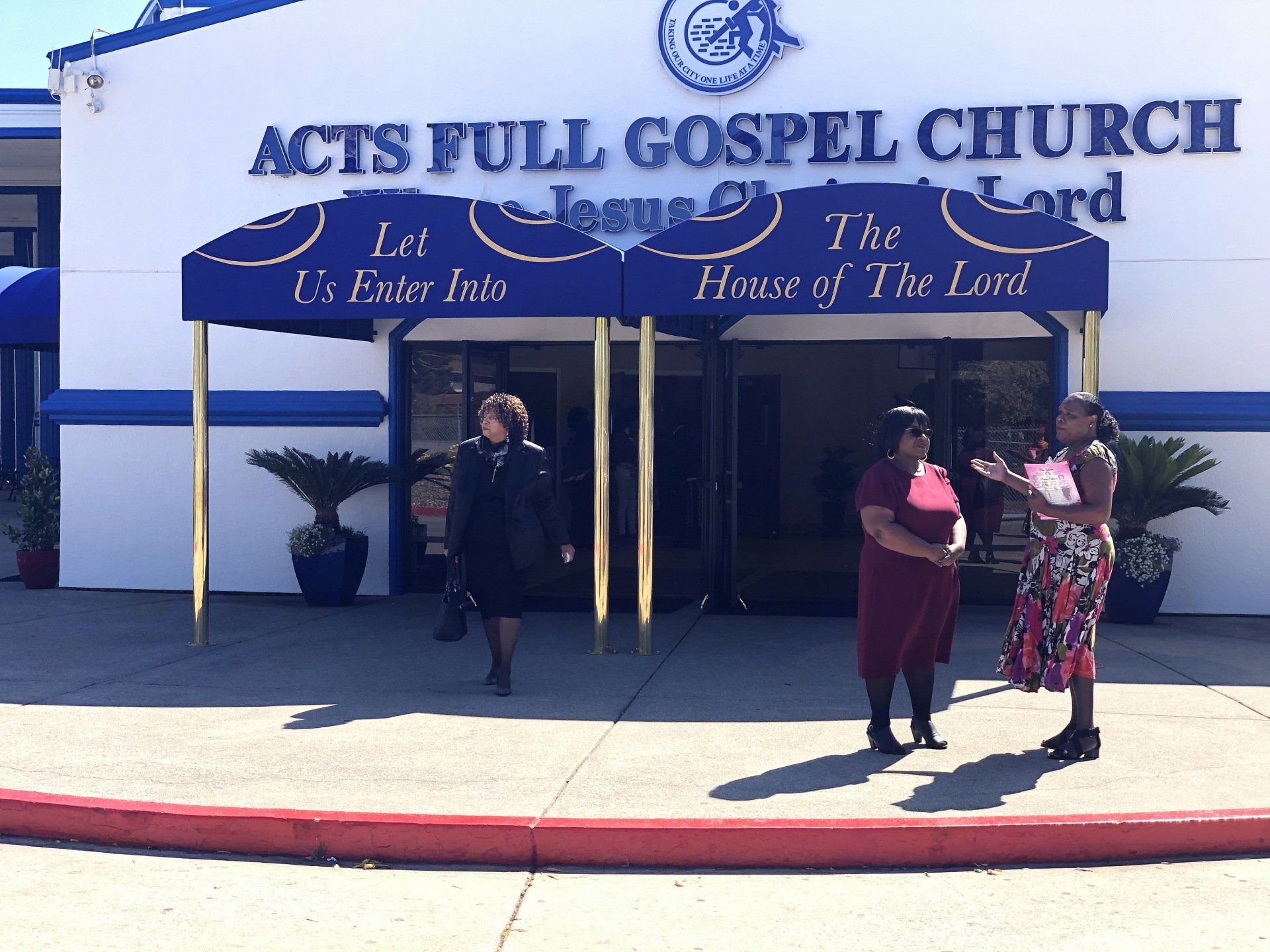 Two women are standing in front of the acts full gospel church