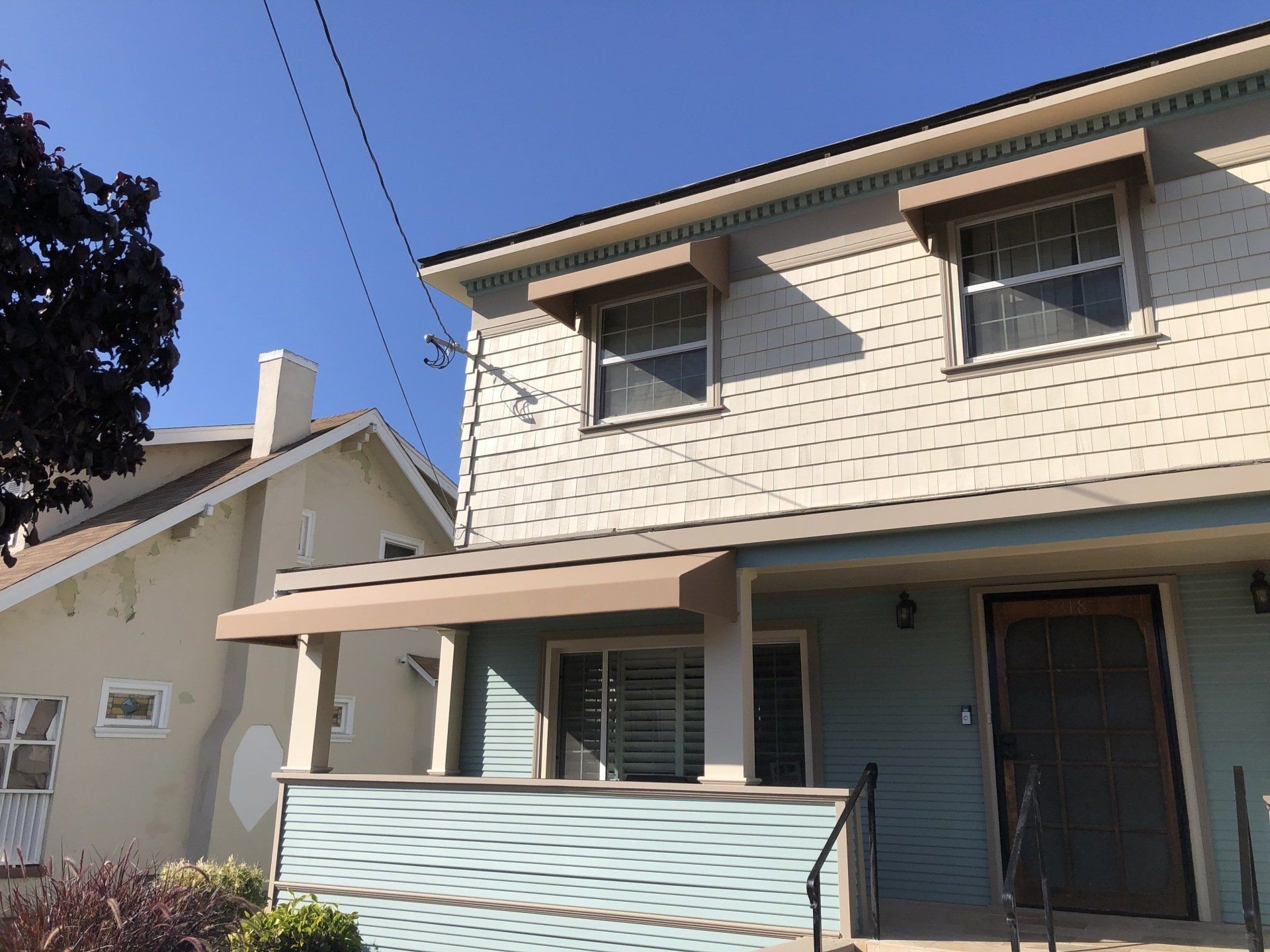 A white house with a brown awning on the front porch.