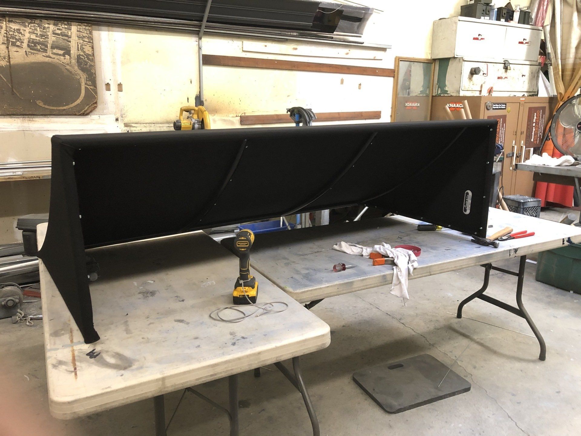 A folding table with a drill on it in a garage.