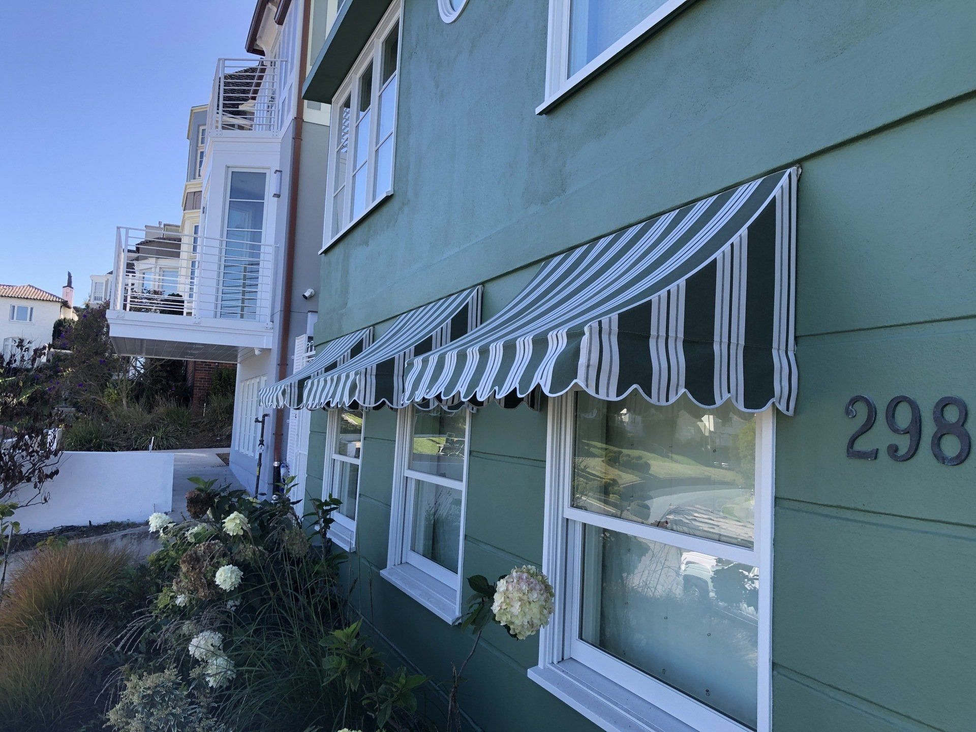 A green building with a striped awning on the windows