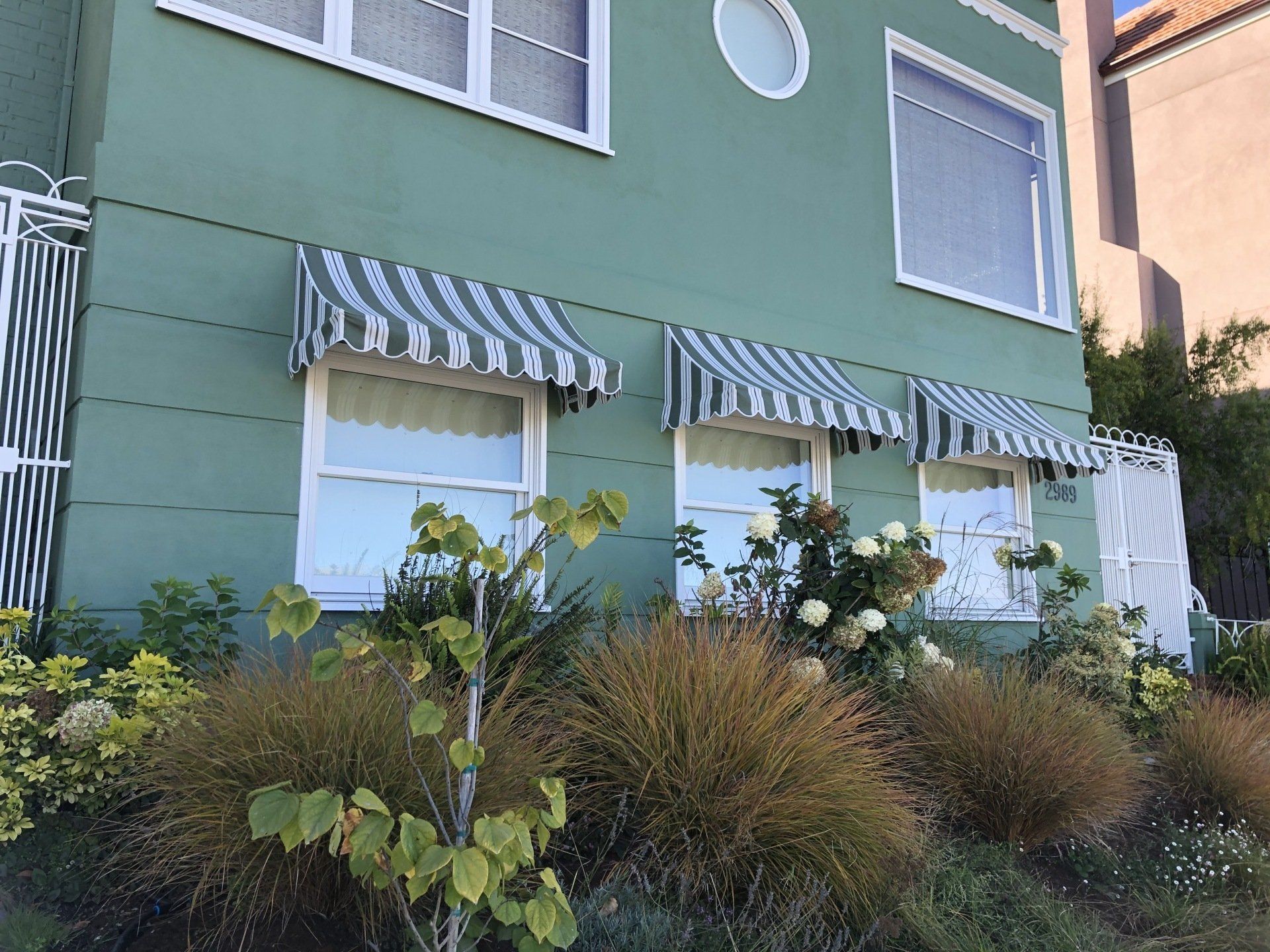 A green building with striped awnings on the windows