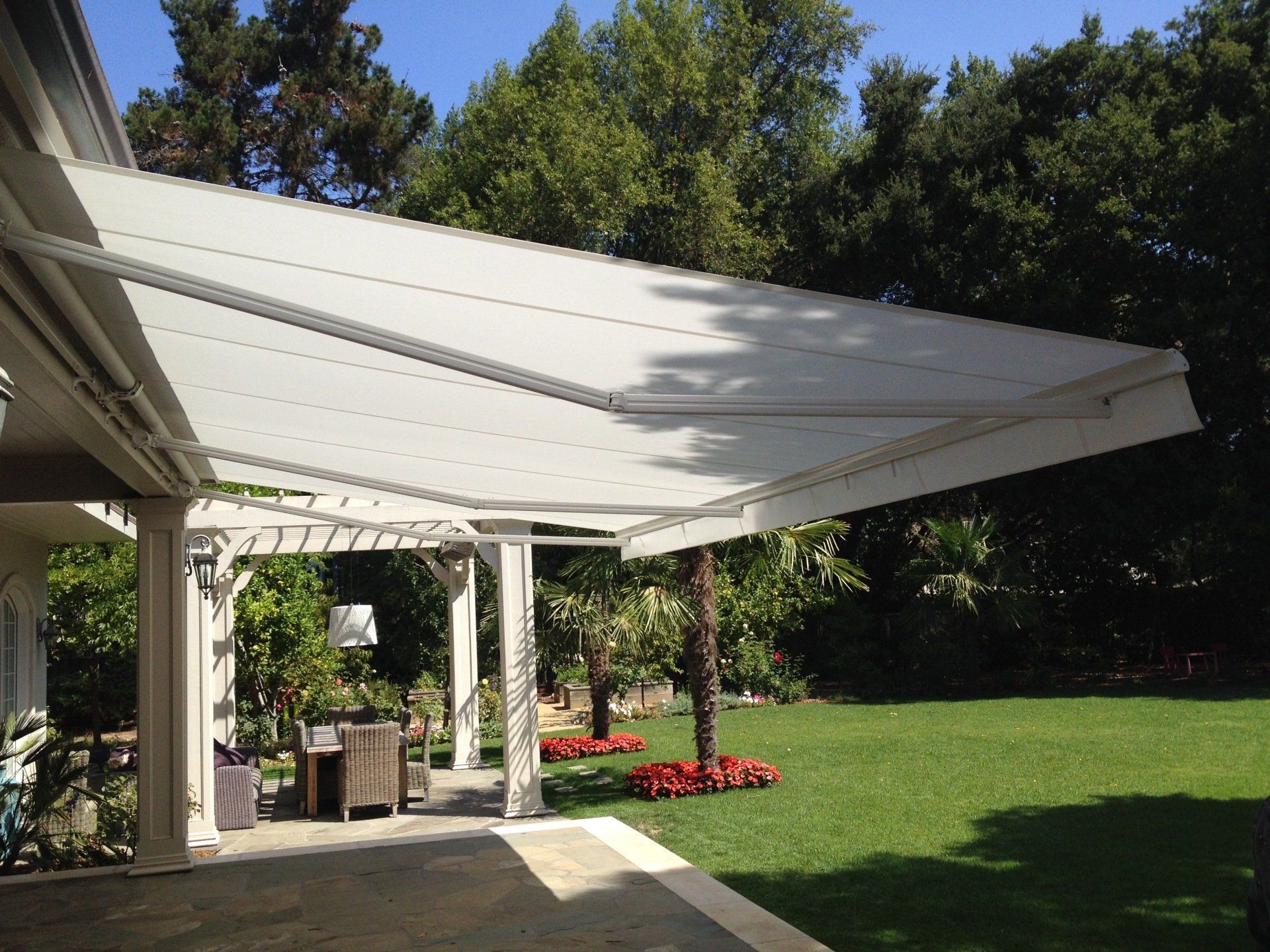 A white awning is covering a patio in a backyard