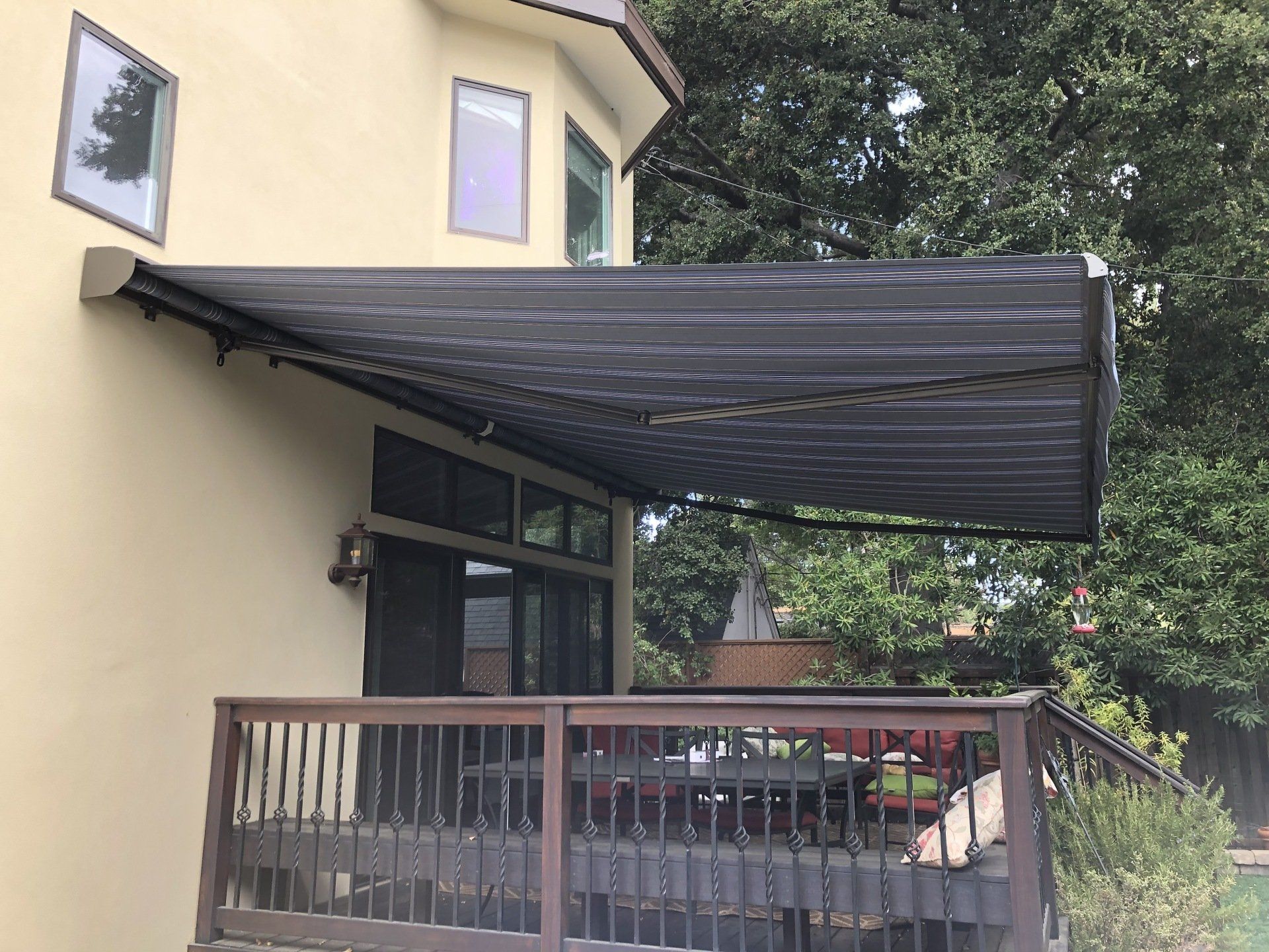 A yellow house with a black awning over a deck.