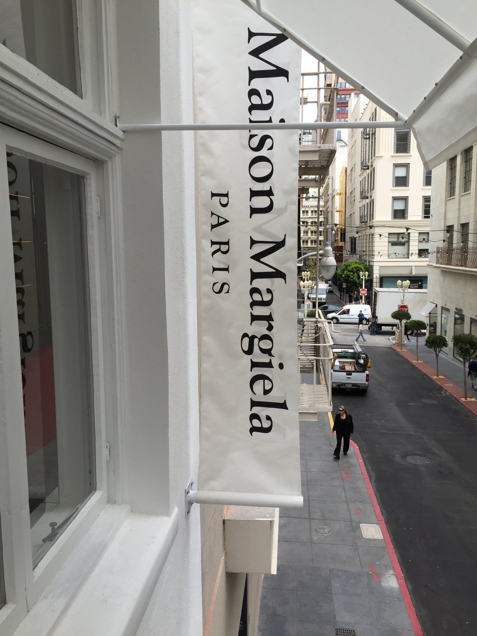 A sign for maison margiela paris hangs above a window