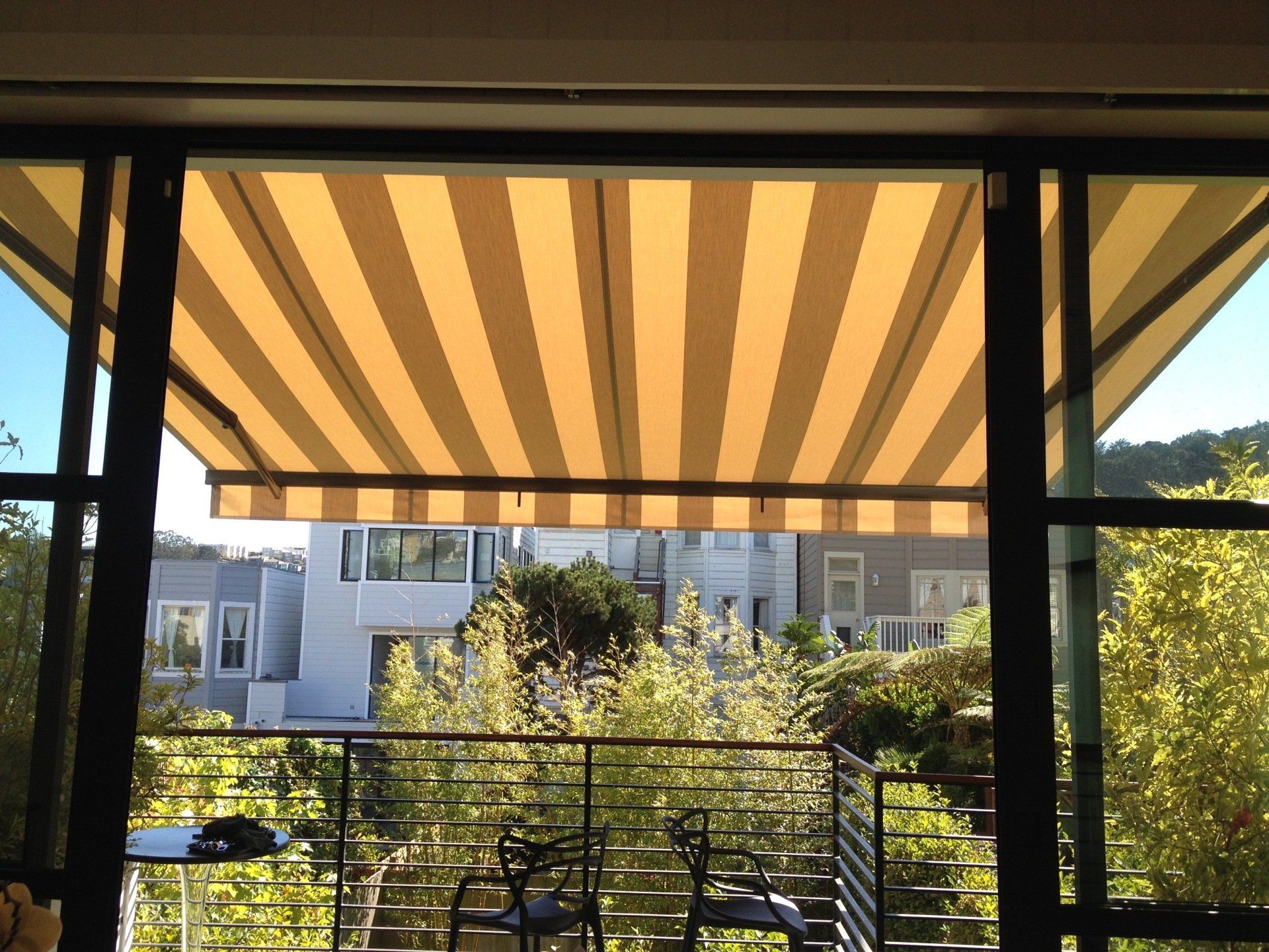 A balcony with a yellow and white striped awning over it