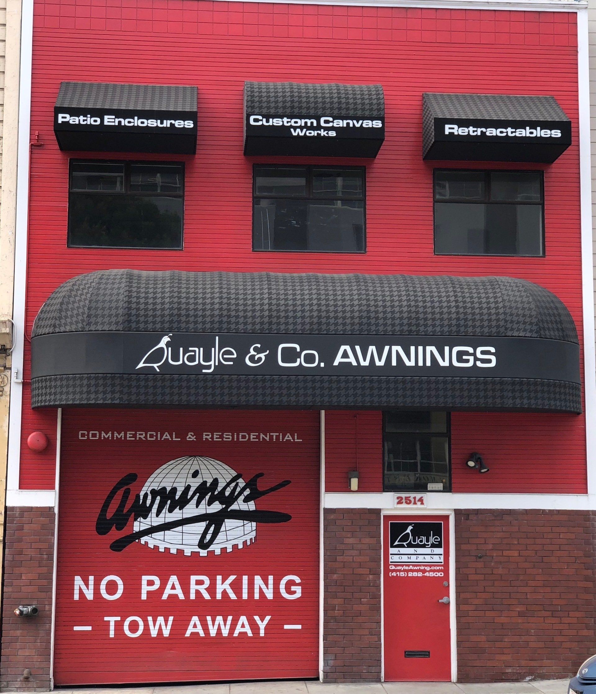 A red building with awnings and a sign that says no parking tow away