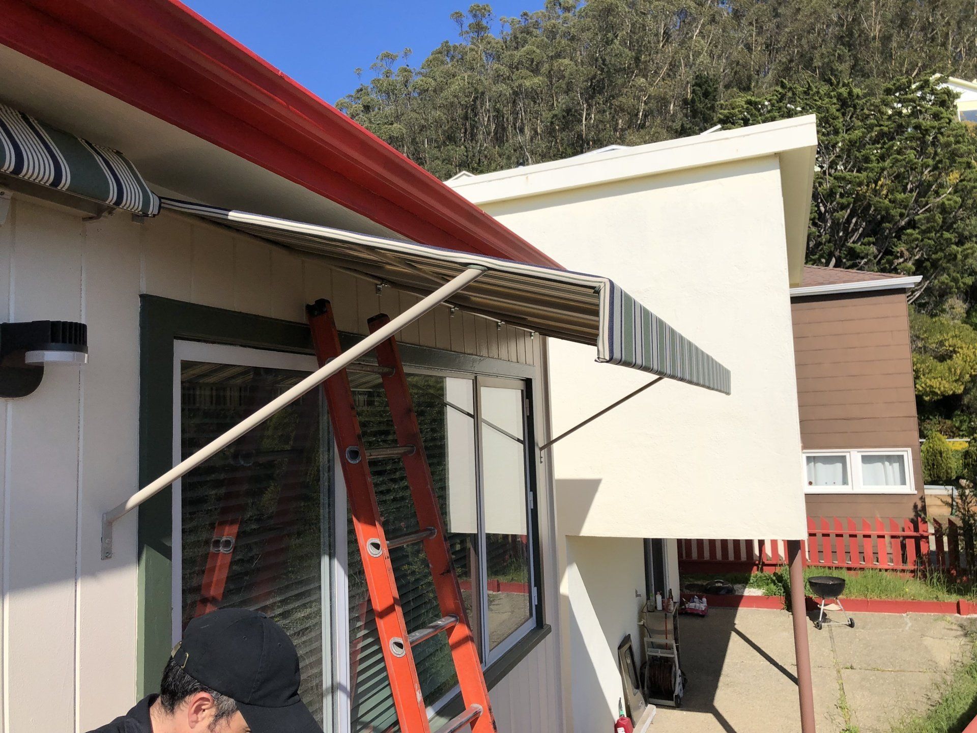 A man is standing next to a ladder on the side of a house.
