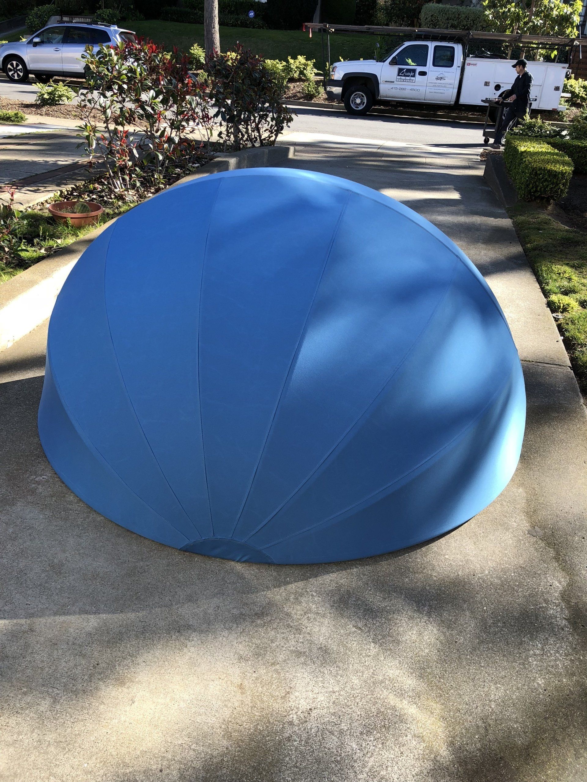 A blue dome is sitting on the sidewalk next to a white truck.