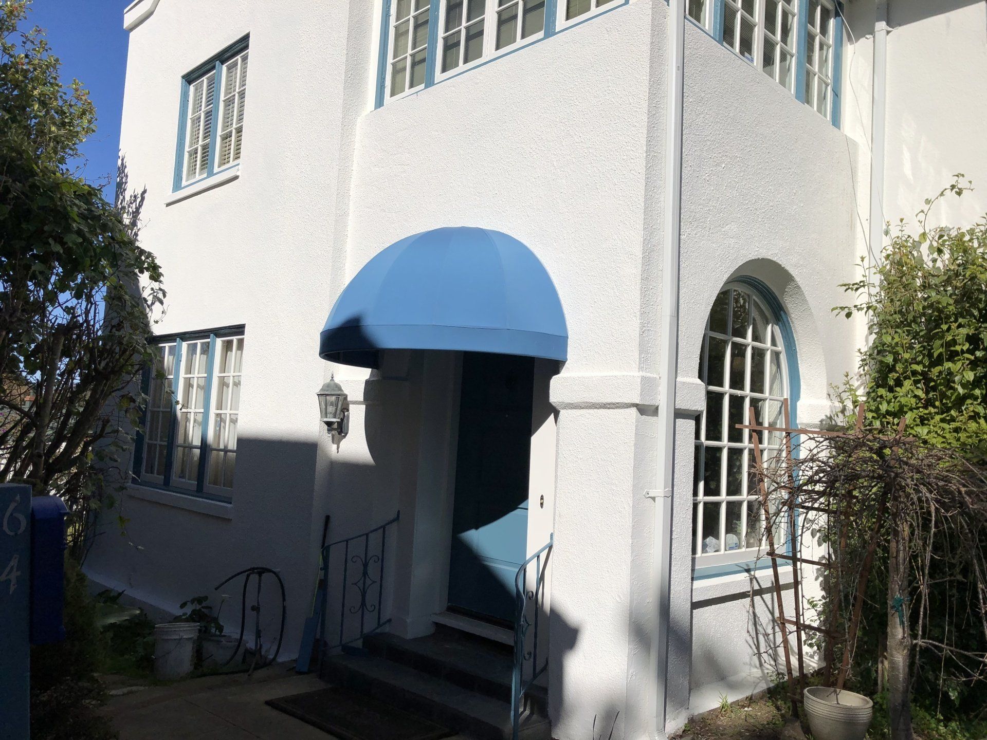 A white house with a blue awning over the entrance