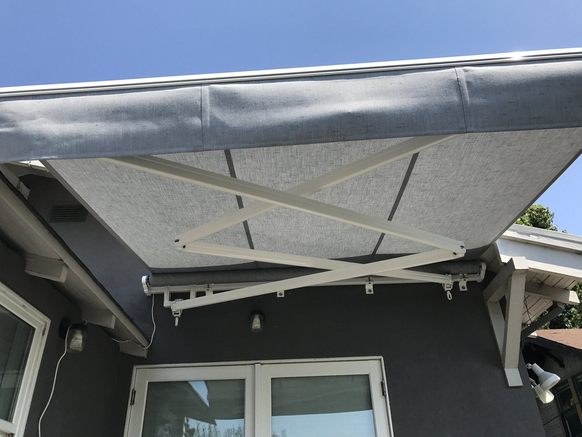 A white awning is hanging over a window on the side of a house.